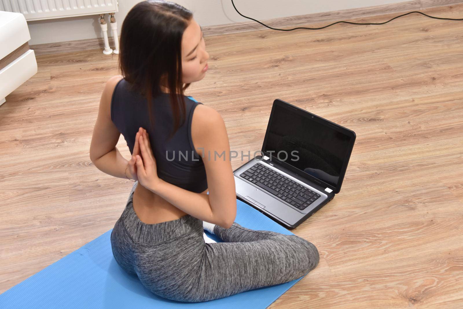 Young asian woman making yoga at home. Carantin and hobby. Home isolation. Online training. Soft focus