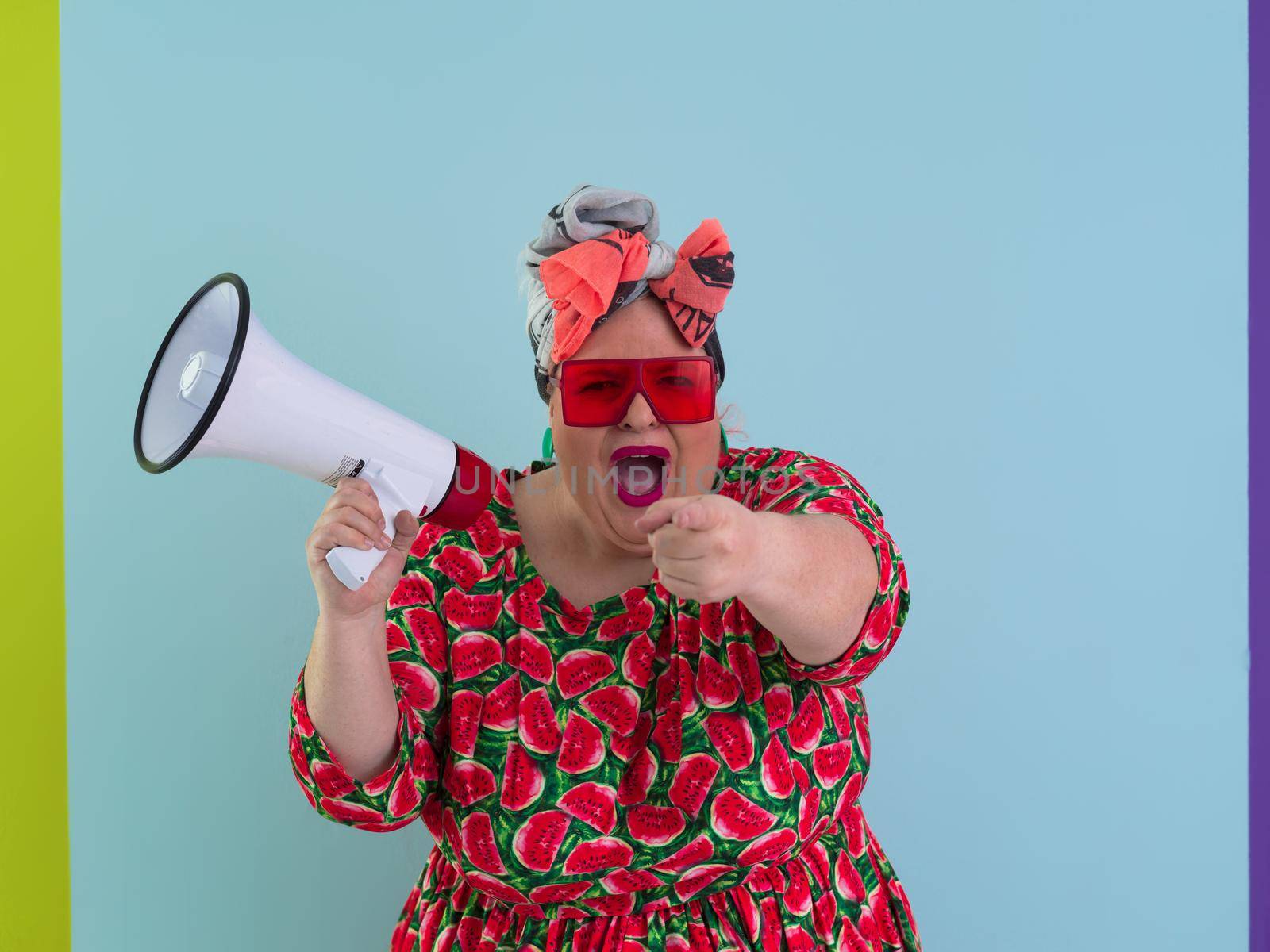 Funny plus size woman posing isolated on cyan background studio portrait. Screaming in a megaphone. People emotions lifestyle concept. Mock up copy space. High quality photo