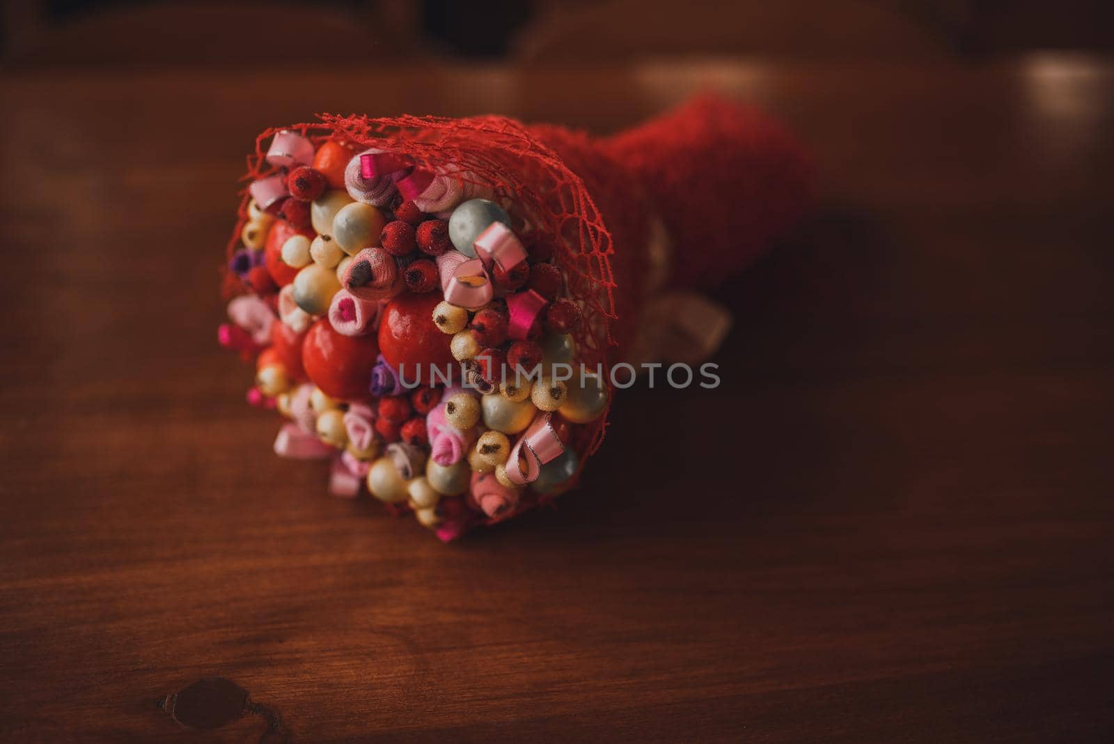 Wedding floral bright beautiful bouquet with small flowers in a wrapper lies on a brown wooden floor background.