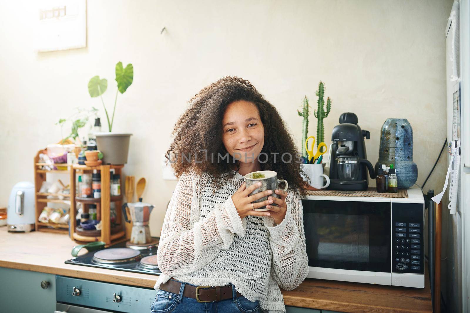 Portrait of a smiling young african woman drinking coffee early in the morning