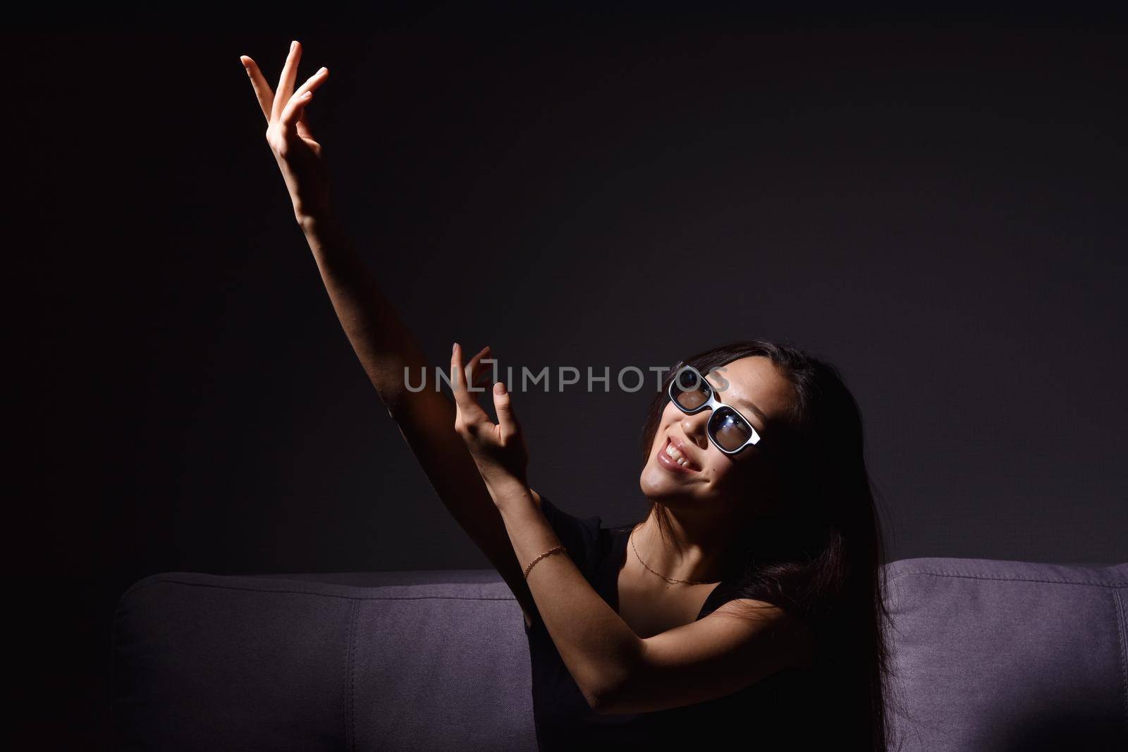 Beautiful young Asian woman watching TV at home. Eating popcorn. Time at home, isolation