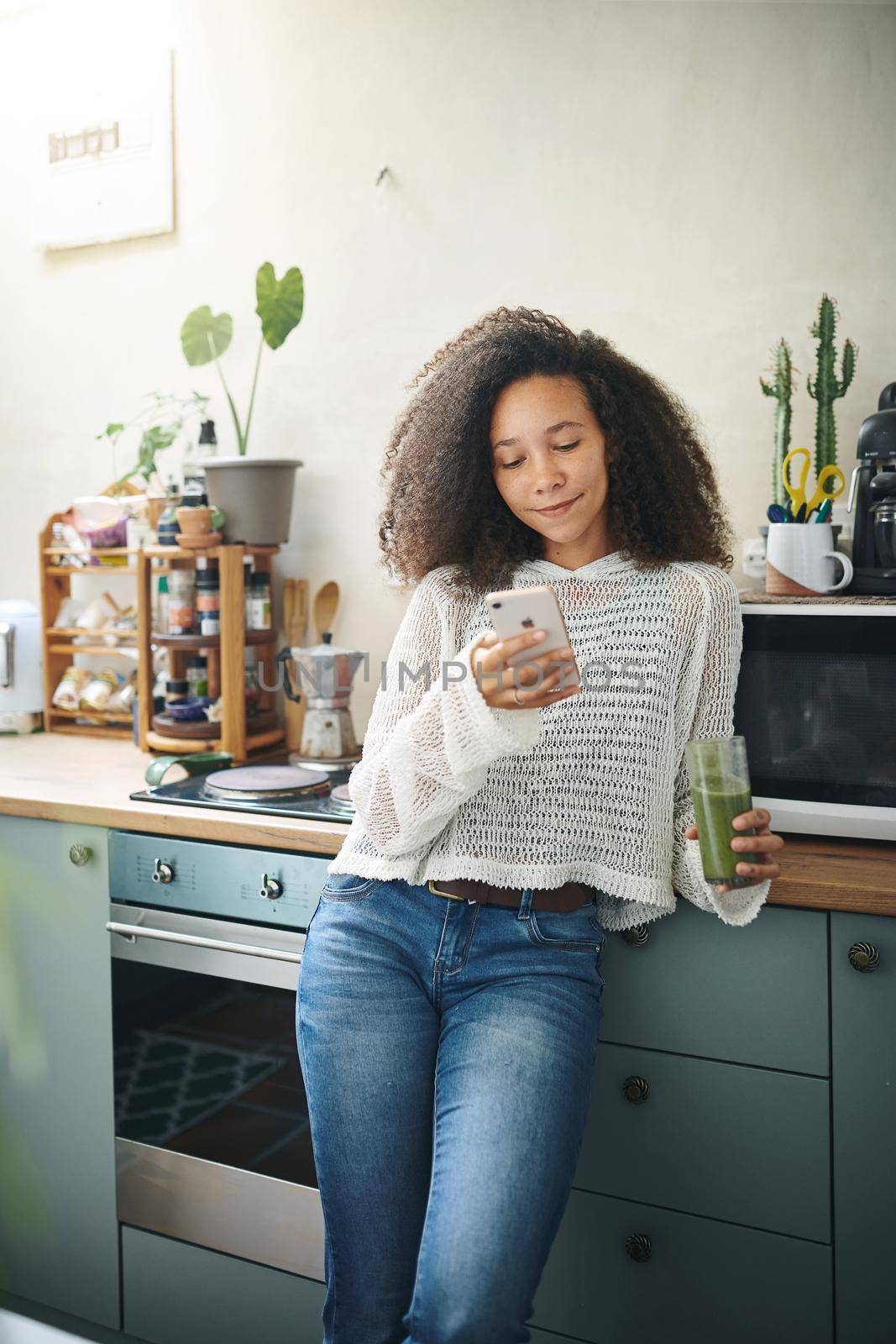 Girl browsing on social media while enjoying her green smoothie. High resolution stock photo