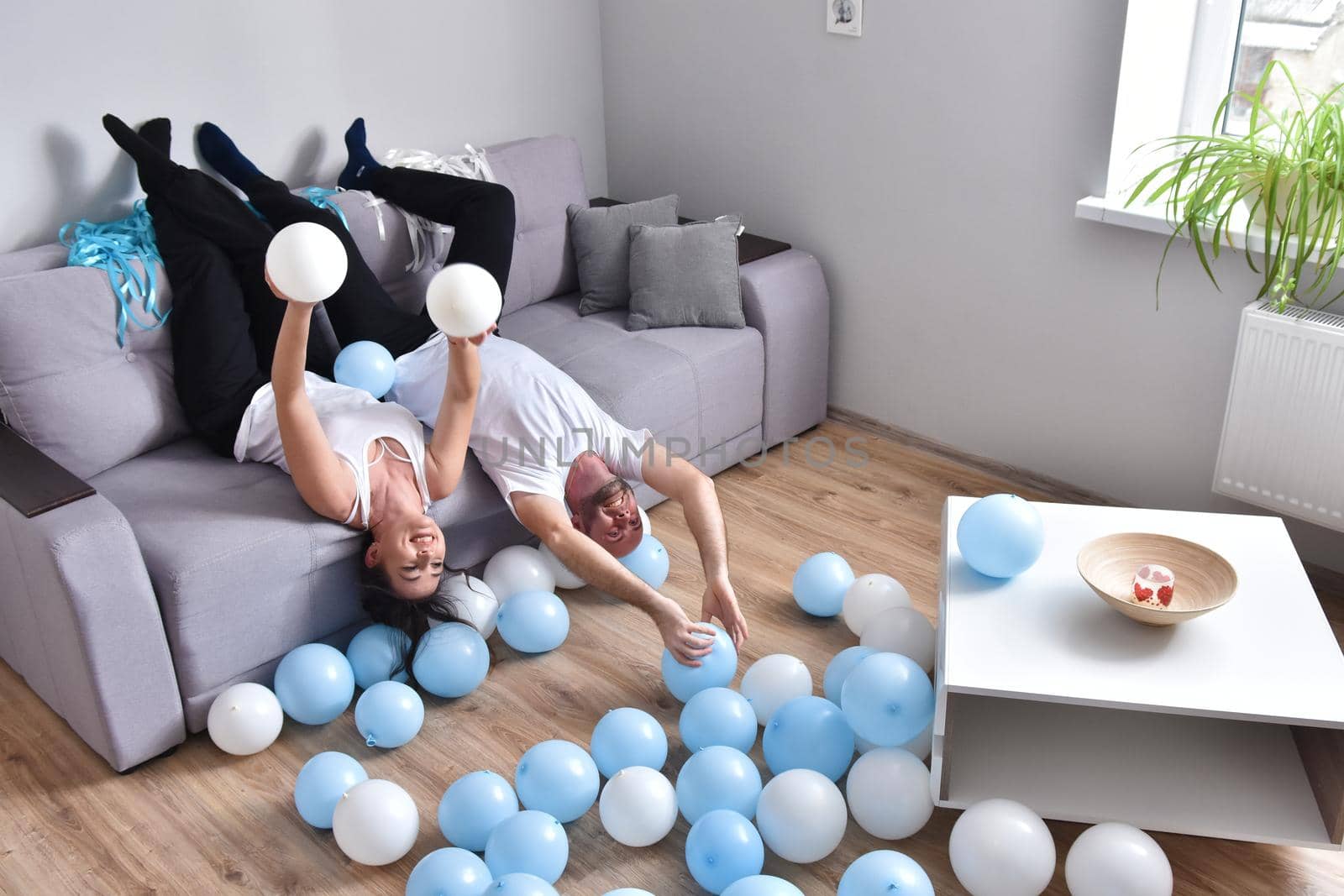 Family couple blowing white and blue balloons. Man and woman preparing before party