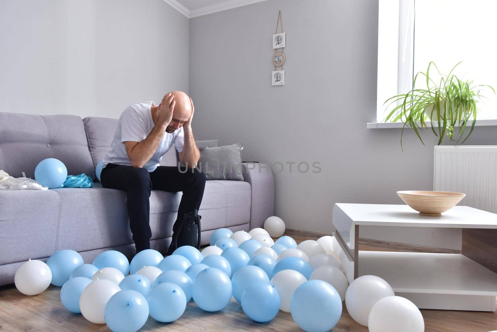 Celebration, holidays, party concept. Happy hairless man preparing to party. Blowing blue and white balloons