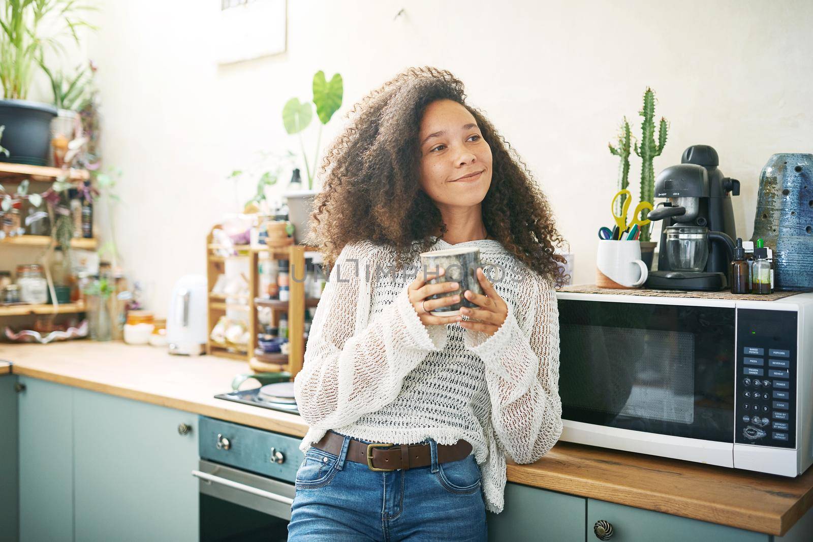 Portrait of a smiling young african woman drinking coffee early in the morning