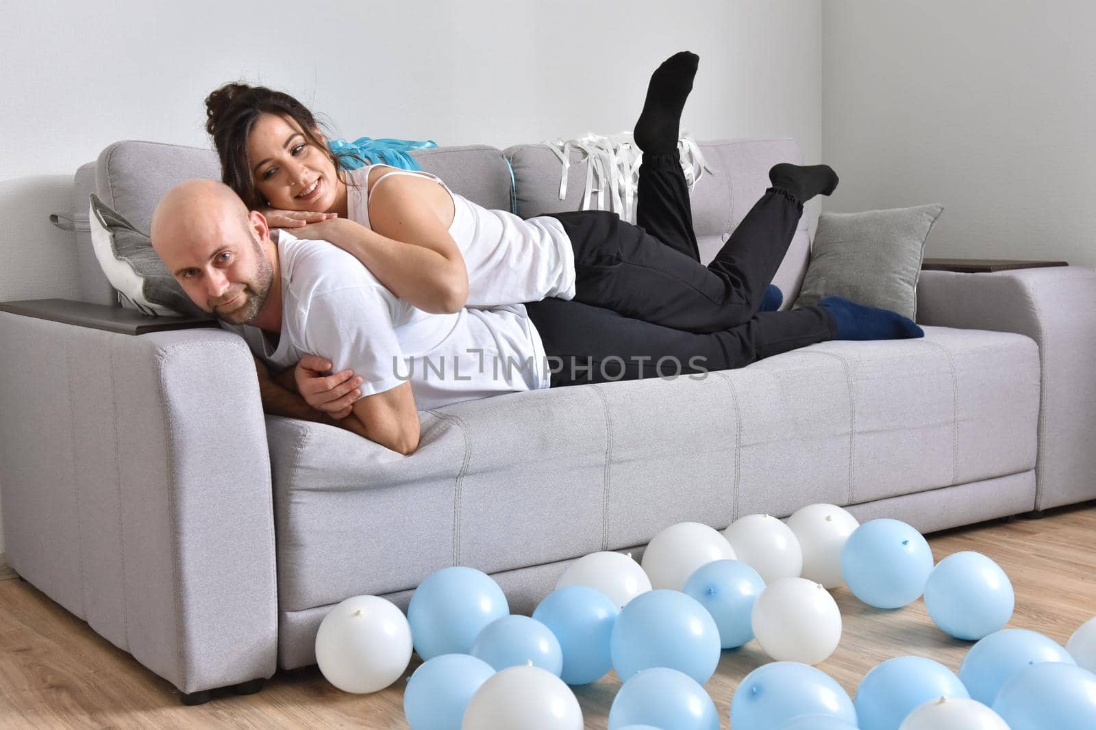 Family couple smiling ans hugging sitting on sofa by Bonda