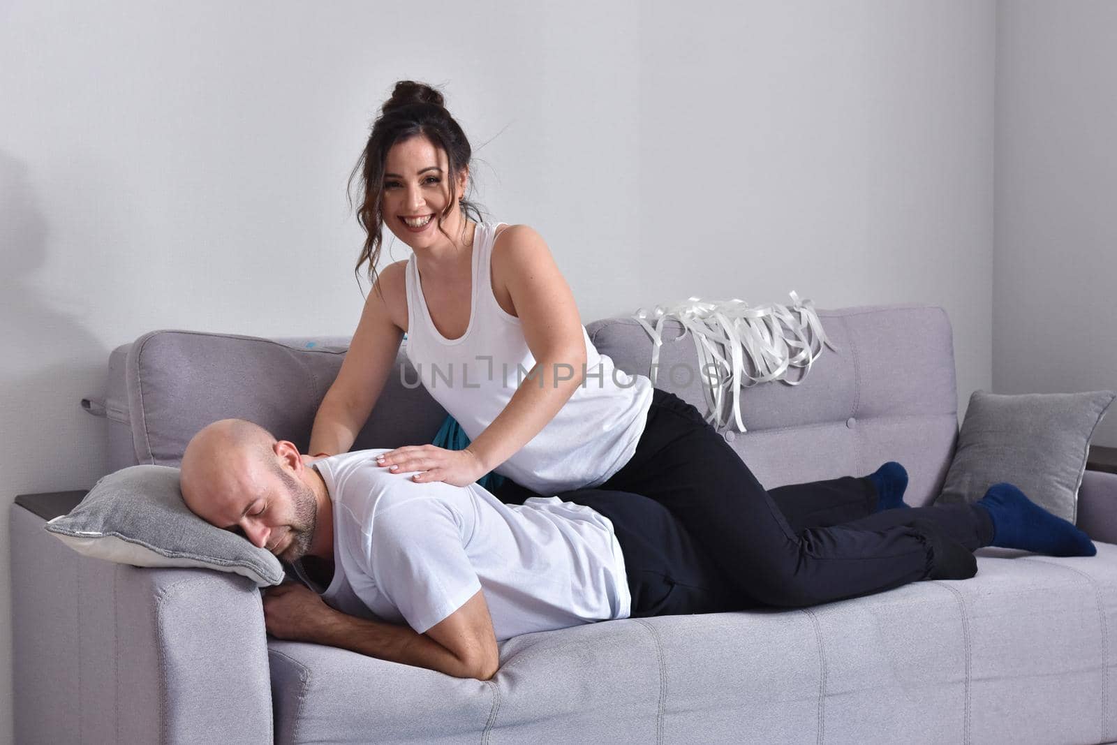 Family couple smiling ans hugging sitting on sofa by Bonda