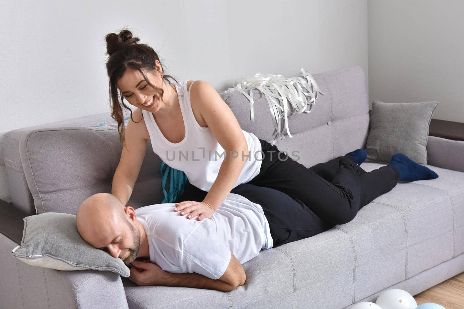 Photo of cheerful romantic caucasian family couple smiling and hugging while sitting on sofa at home. Man and woman in love