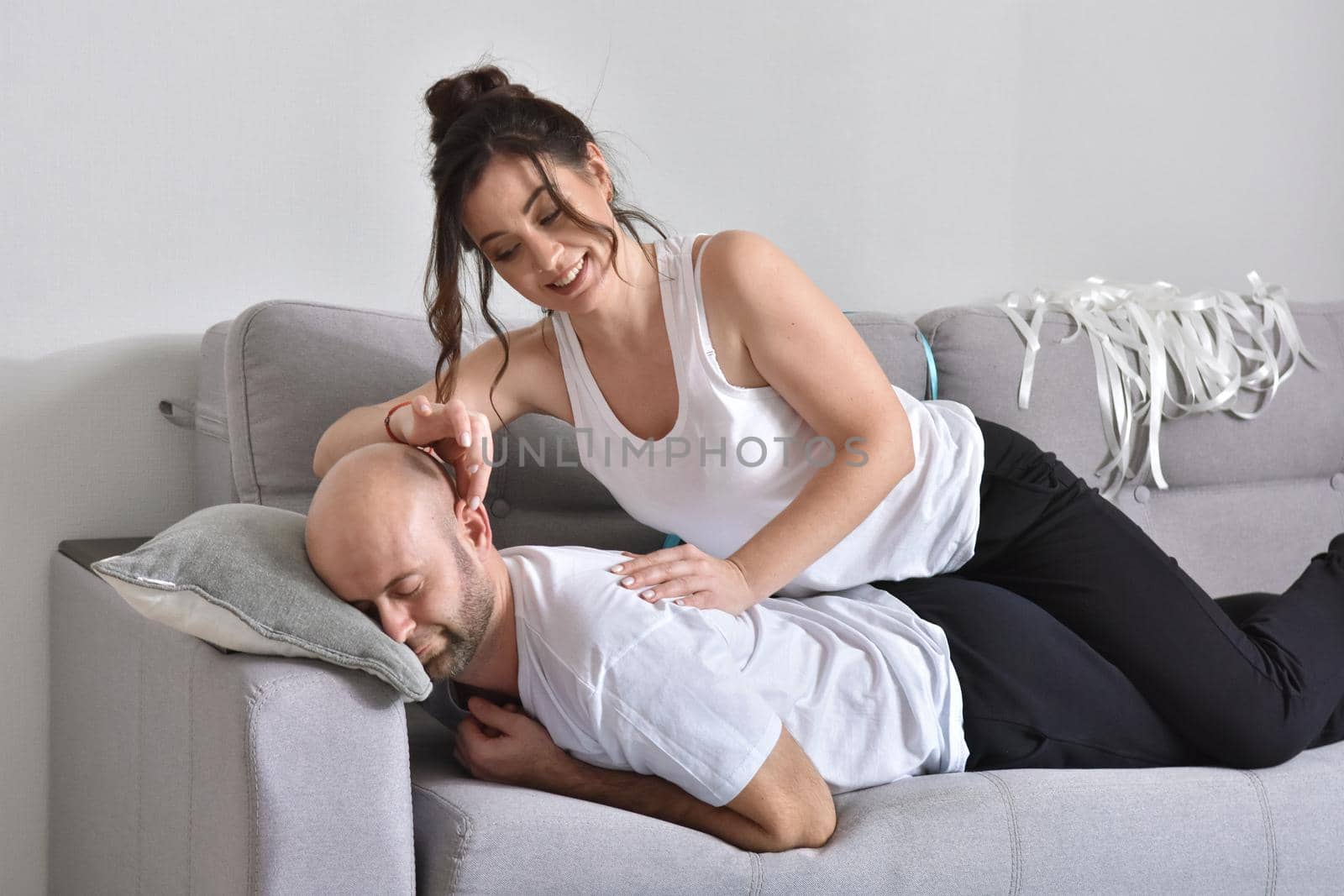 Photo of cheerful romantic caucasian family couple smiling and hugging while sitting on sofa at home. Man and woman in love