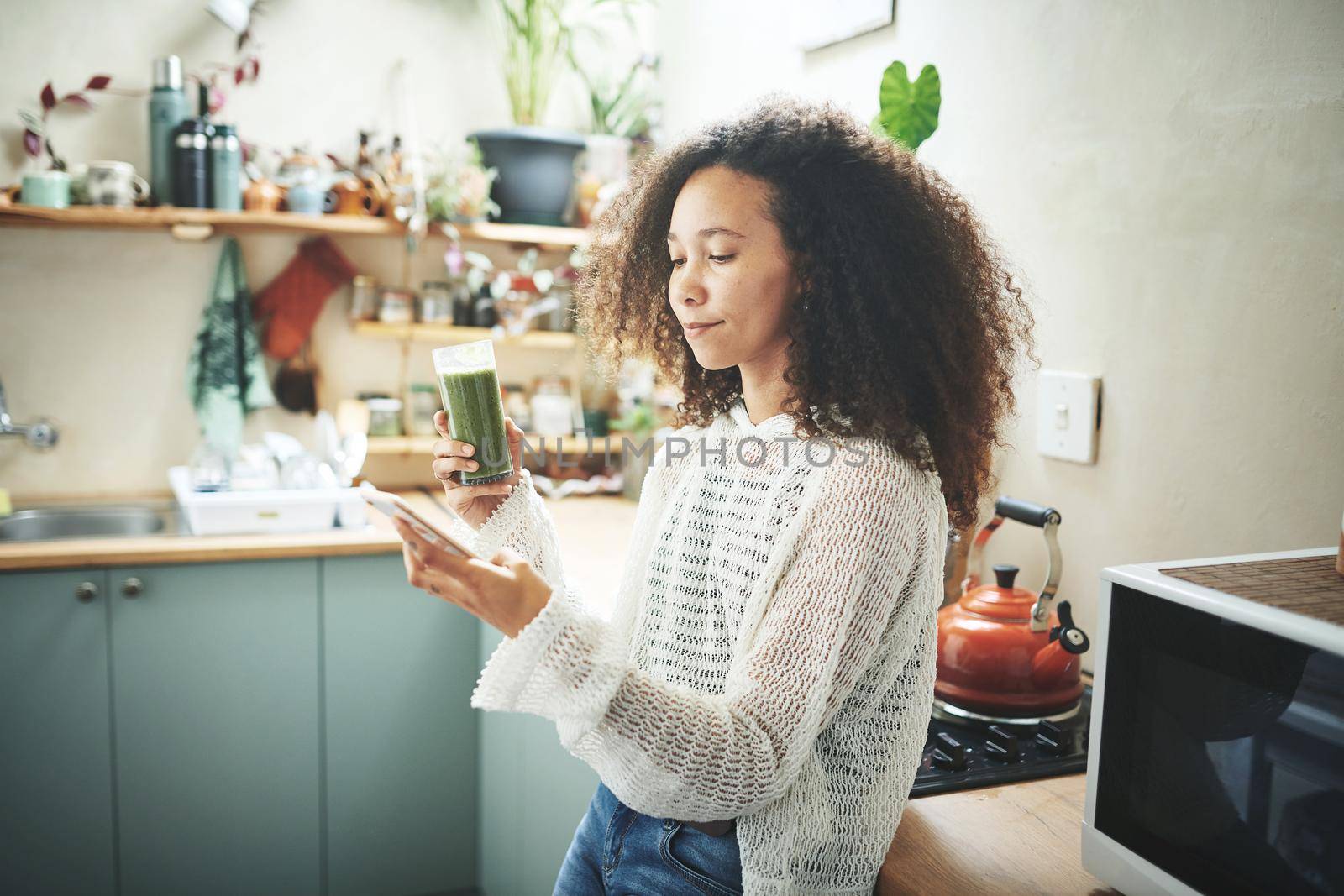 Young african girl browsing on social media while enjoying her green smoothie