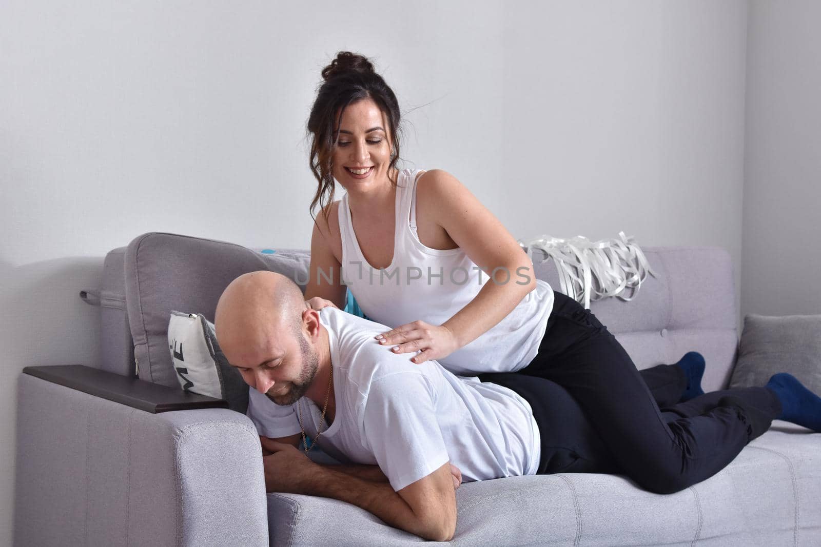 Family couple smiling ans hugging sitting on sofa by Bonda