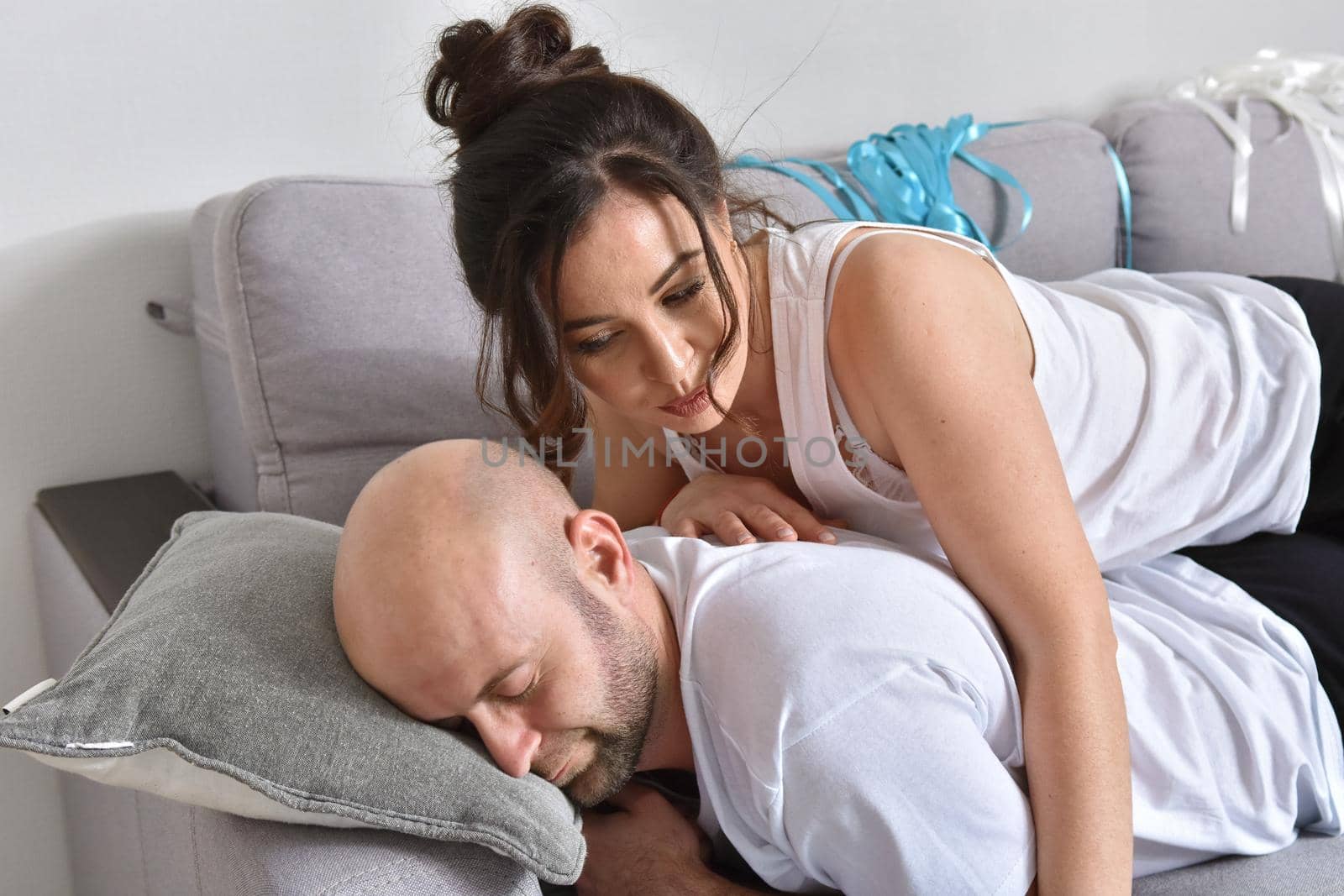 Photo of cheerful romantic caucasian family couple smiling and hugging while sitting on sofa at home. Man and woman in love