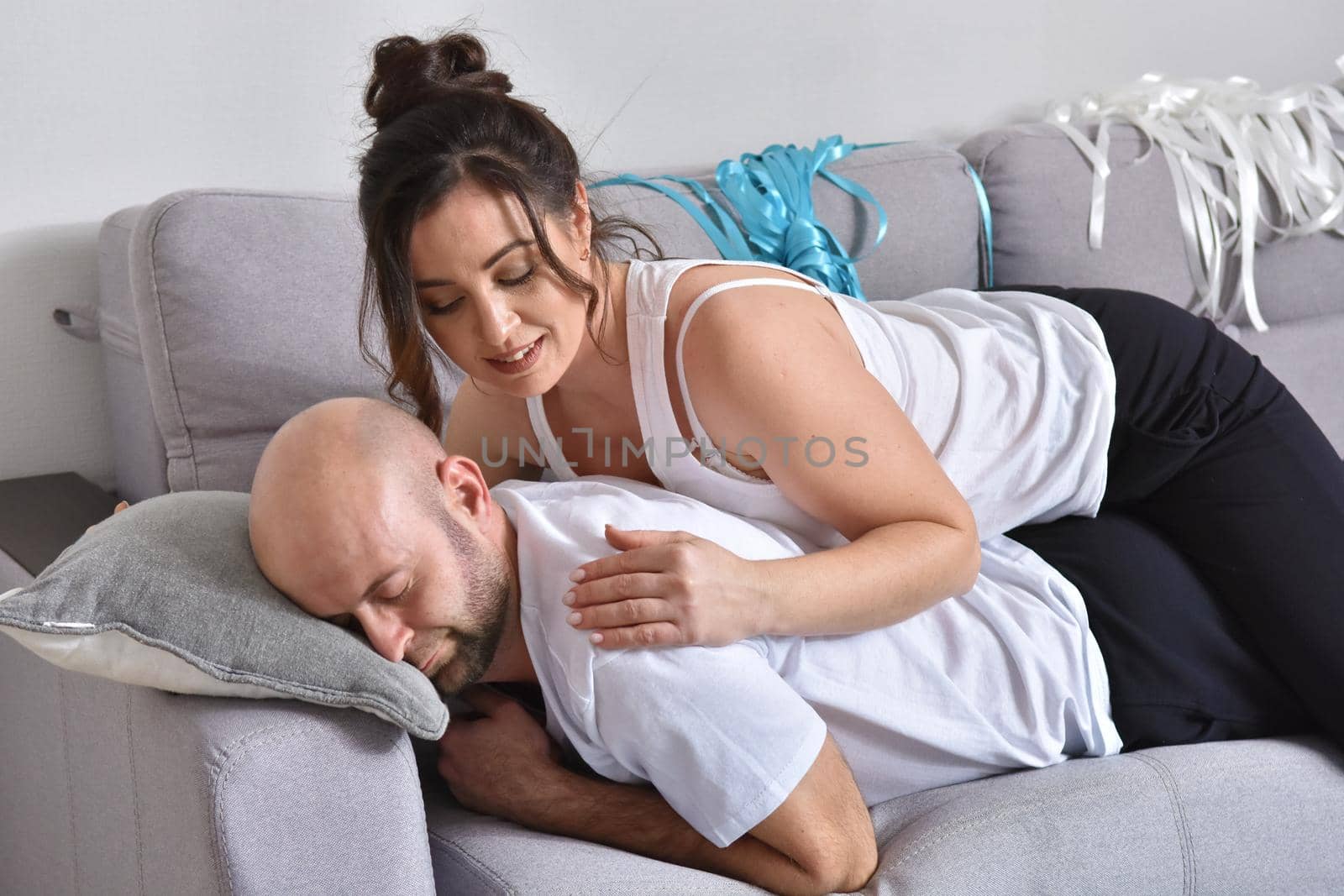 Photo of cheerful romantic caucasian family couple smiling and hugging while sitting on sofa at home. Man and woman in love