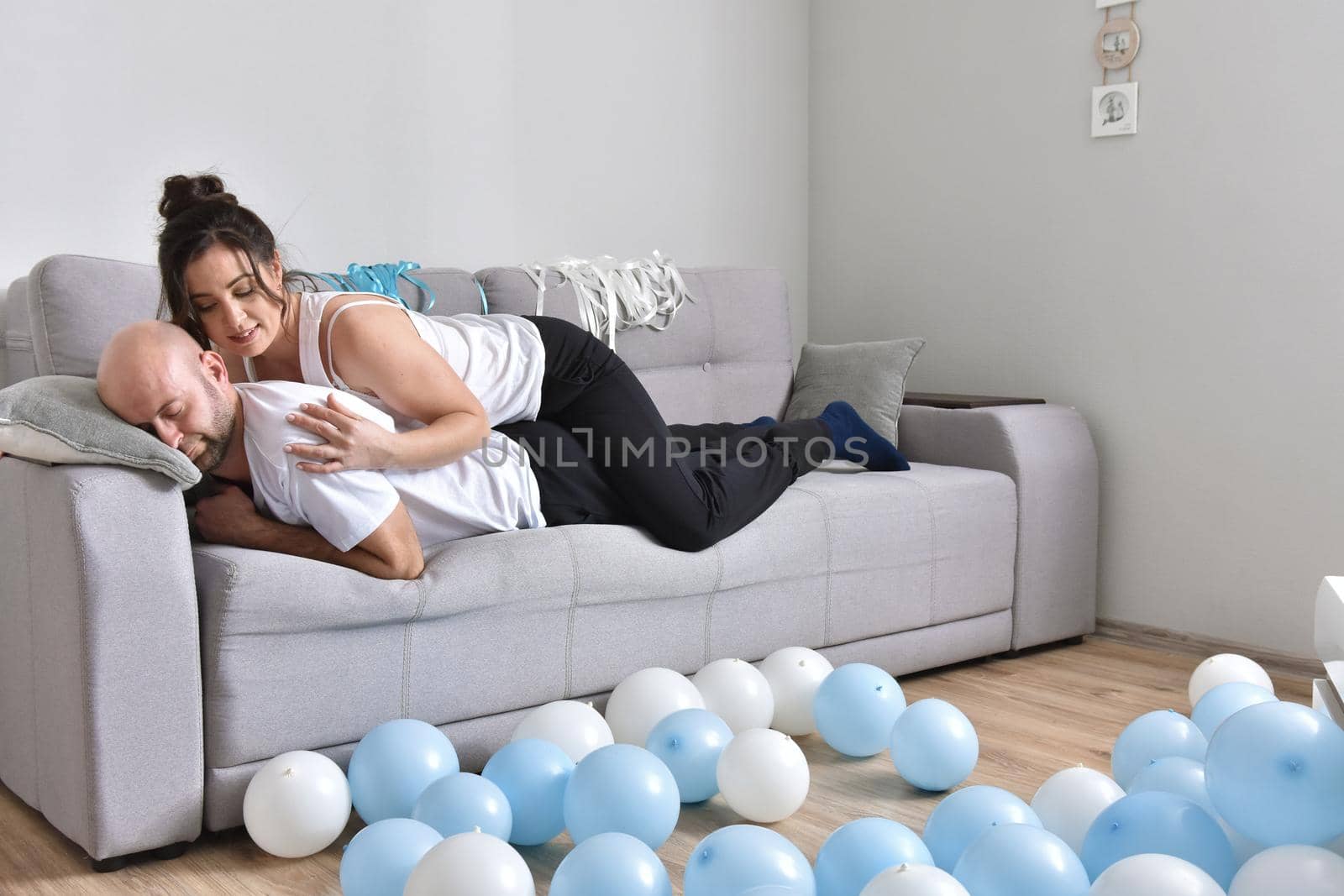 Family couple smiling ans hugging sitting on sofa by Bonda