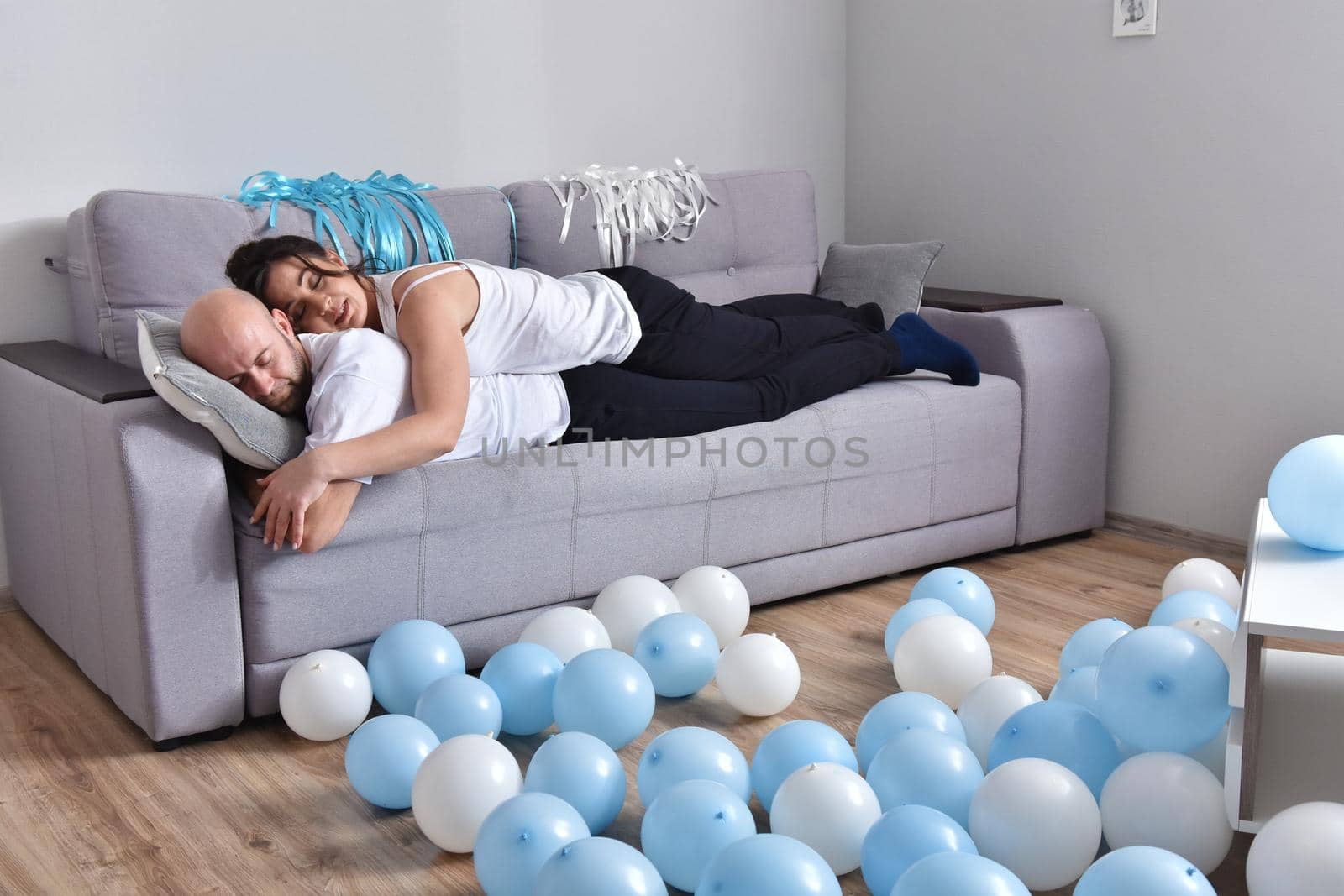 Family couple smiling ans hugging sitting on sofa by Bonda