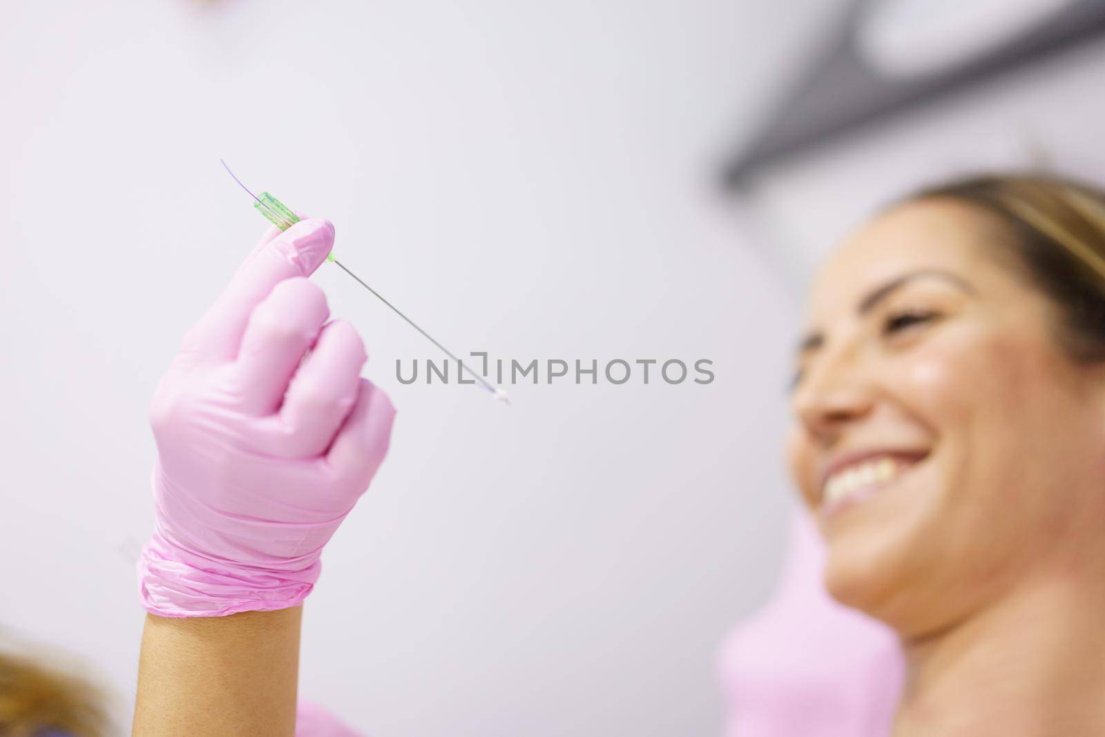 Doctor showing a PDO treatment suture thread to her patient. by javiindy