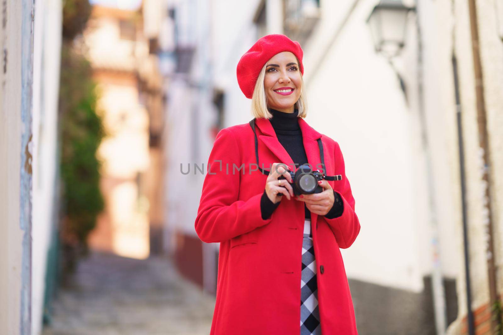 Happy female tourist taking photos of town streets by javiindy