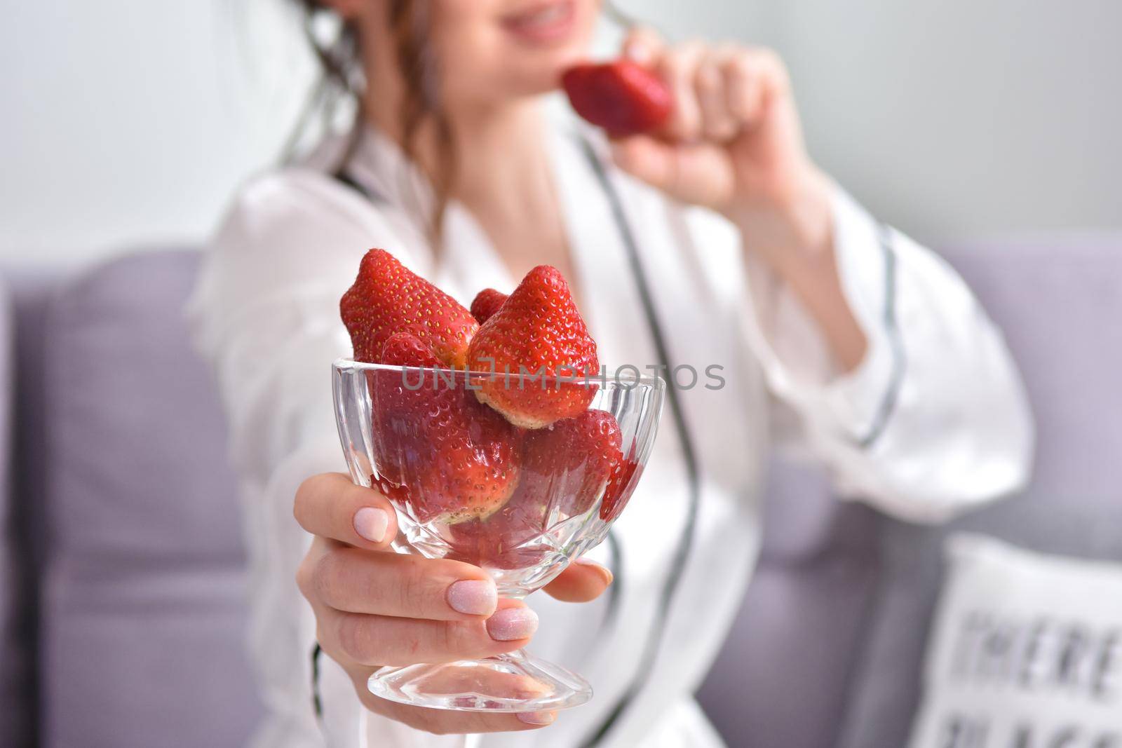 Portrait of happy young brunette woman holding bowl of juicy red strawberries