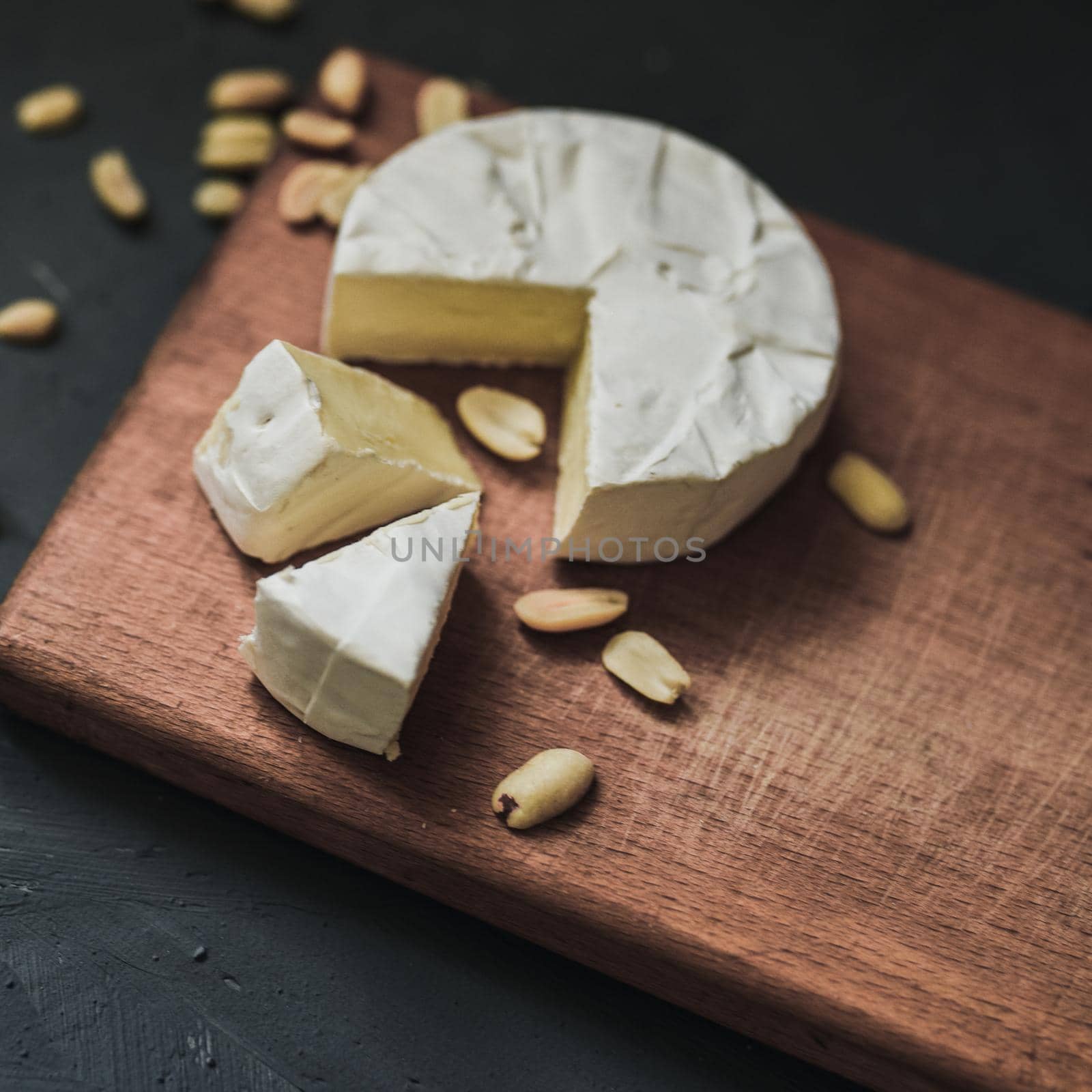 cheese camembert with mold and nuts on wooden board by AndriiDrachuk