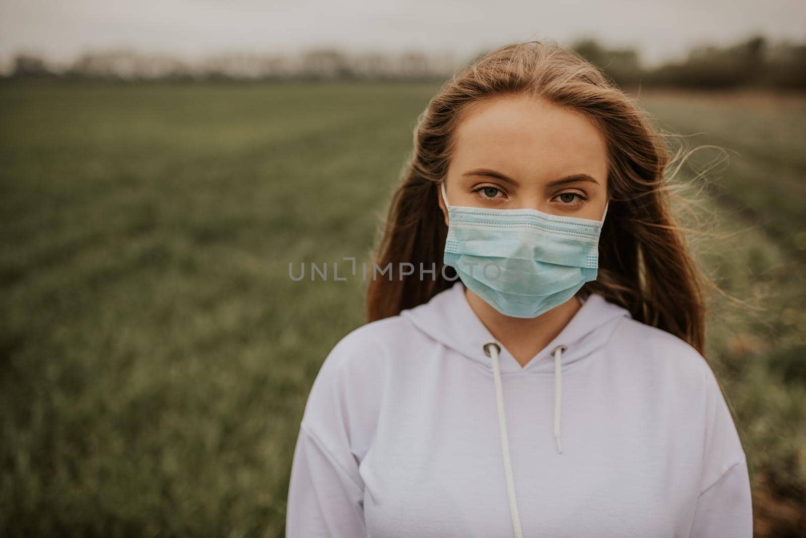 Young blond European woman in a protective mask outdoors.
