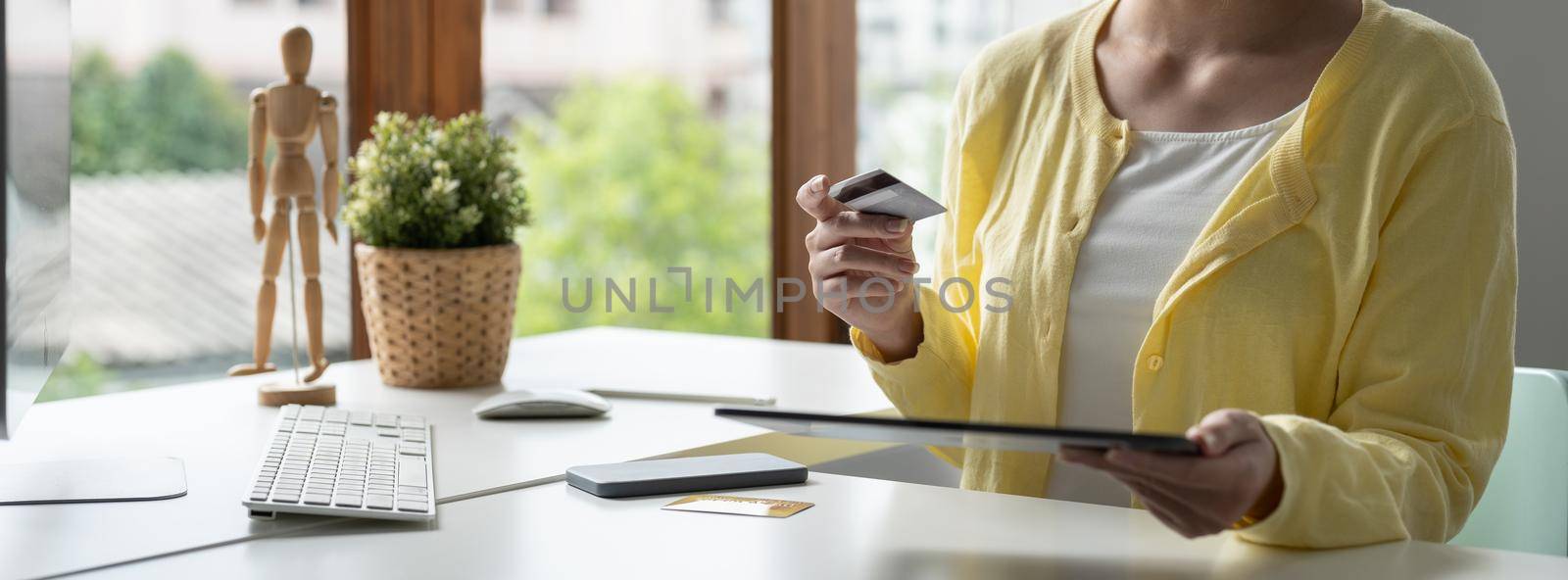 Close up of girl hold bank credit card, shopping online using mobile phone, buying goods or ordering online, entering bank accounts and details in online banking offer. by nateemee