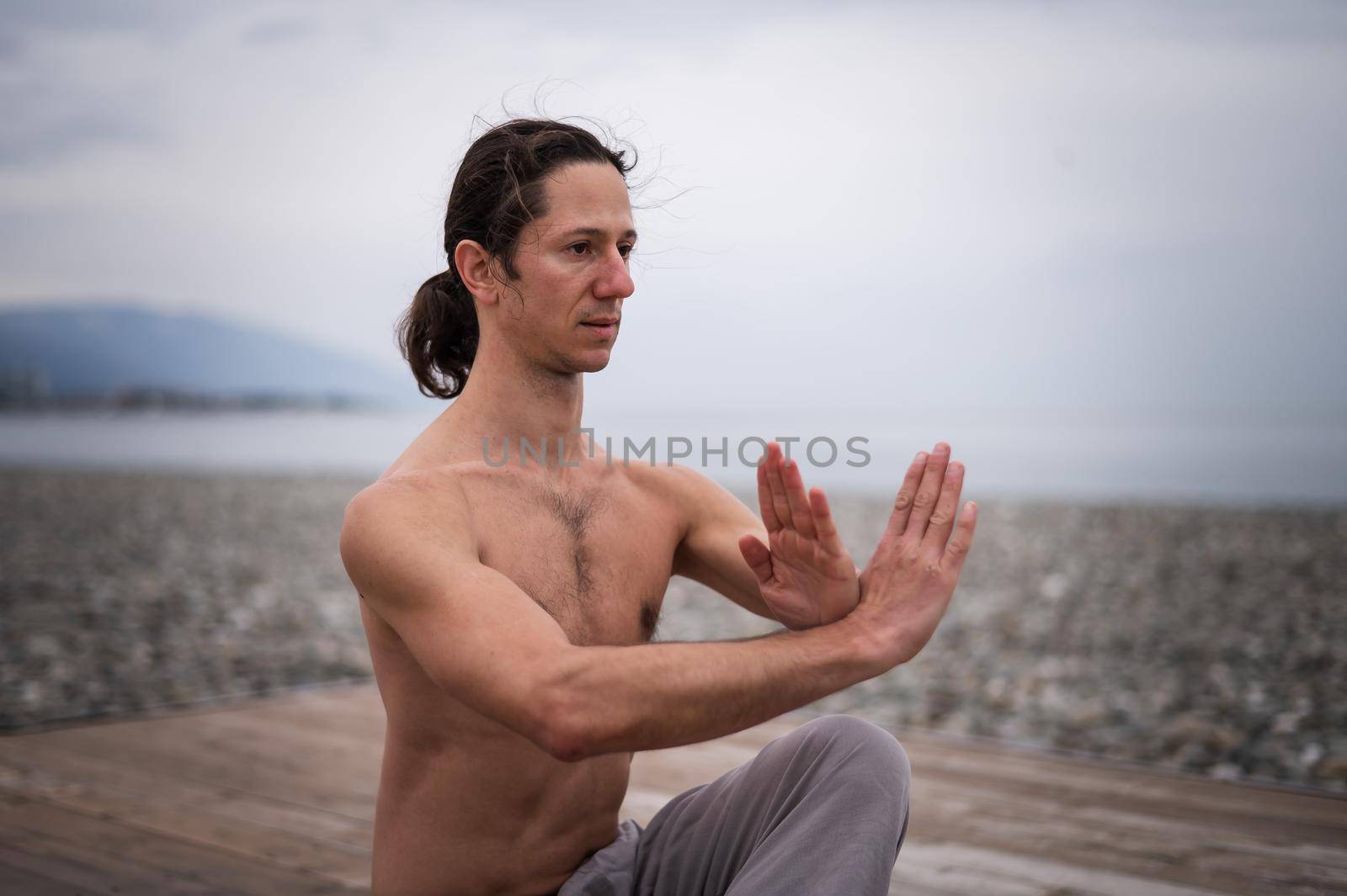 Caucasian man with naked torso practicing wushu on the seashore. by mrwed54