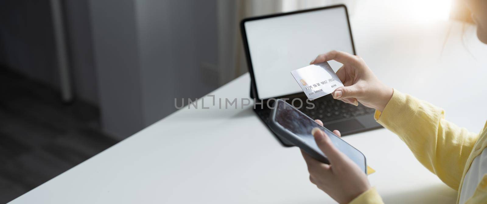 Close up of girl hold bank credit card, shopping online using mobile phone, buying goods or ordering online, entering bank accounts and details in online banking offer
