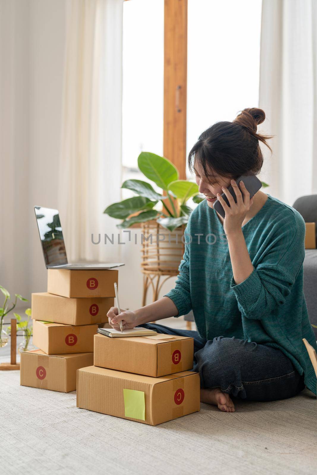 Entrepreneurs Small Business SME Independent woman work at home use smartphones and laptops for commercial checking, online marketing, packing boxes, SME sellers, concept, e-commerce team, online sales.