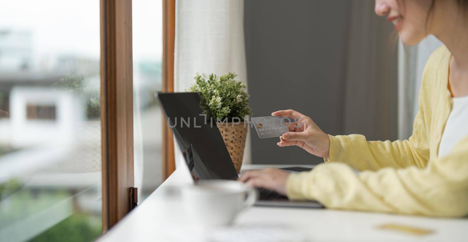 Close up of girl hold bank credit card and type on laptop, shopping online using computer, buying goods or ordering online, entering bank accounts and details in online banking offer.