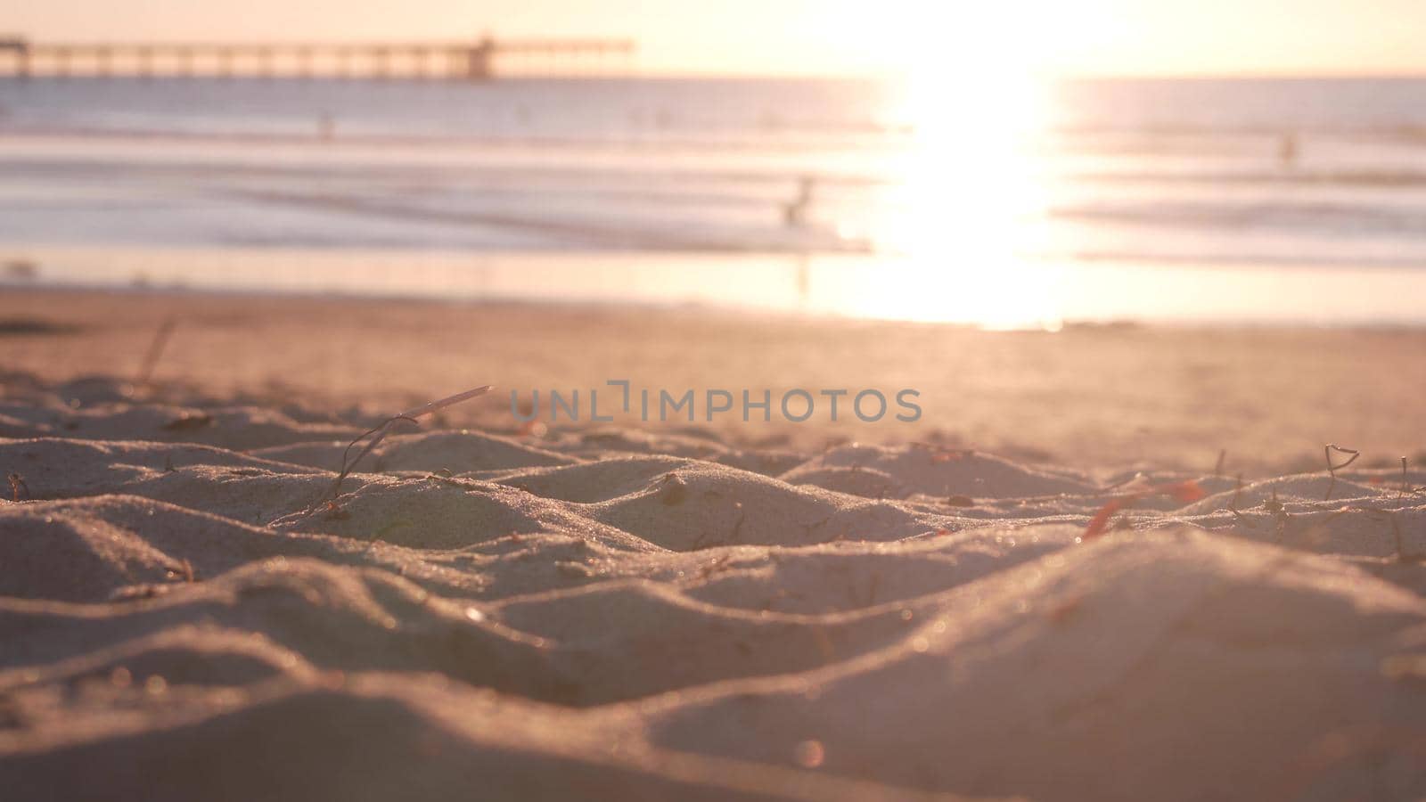People walking on sandy Ocean Beach by pier at sunset, California coast, USA. by DogoraSun