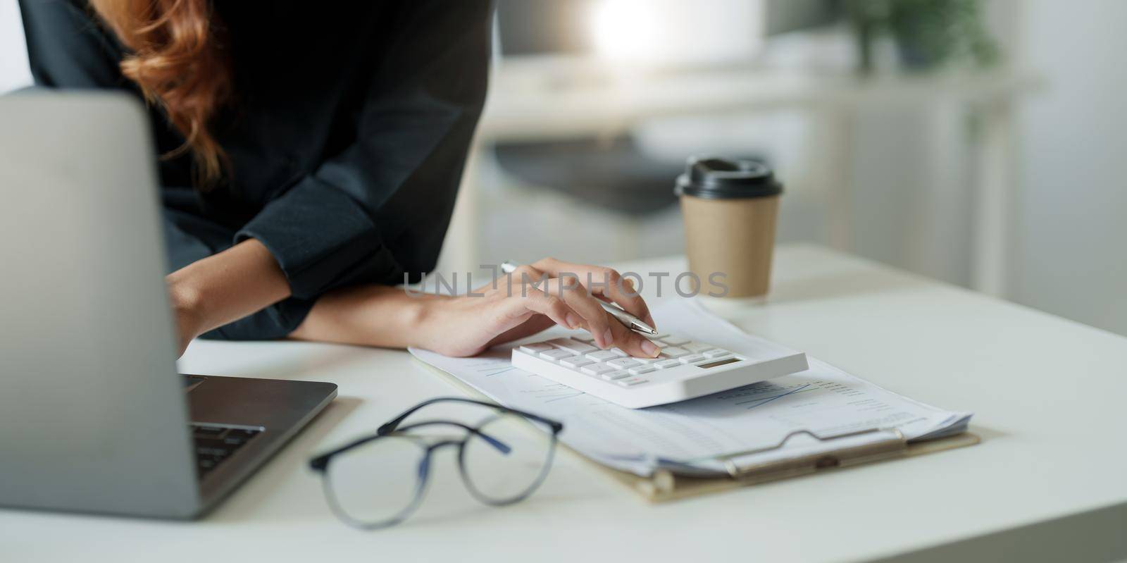 businesswoman or accountant working pointing graph discussion and analysis data charts and graphs and using a calculator to calculate numbers.Business finances and accounting concept.