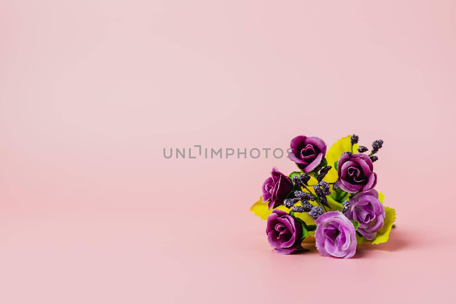 Artificial purple rose bouquet on pink background for love and Valentine's day concep