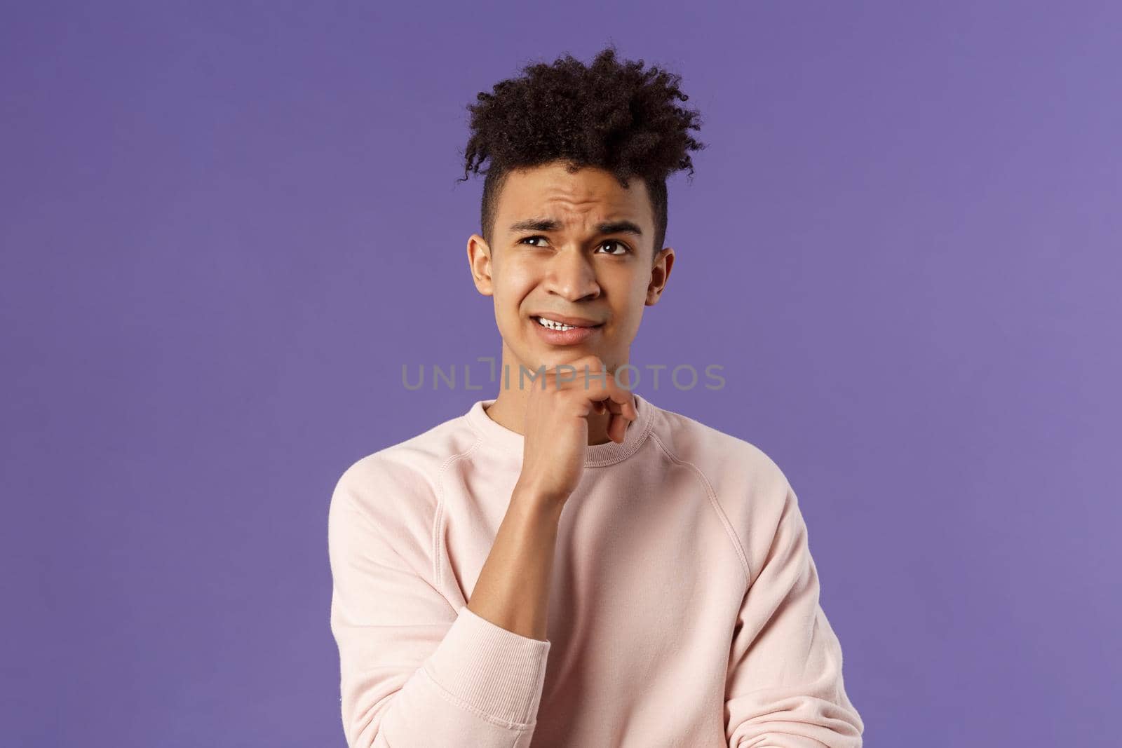 Close-up portrait of indecisive, puzzled young man facing difficult choice, look up thoughtful, touch chin and grimacing while thinking, making-up idea or decision, purple background by Benzoix