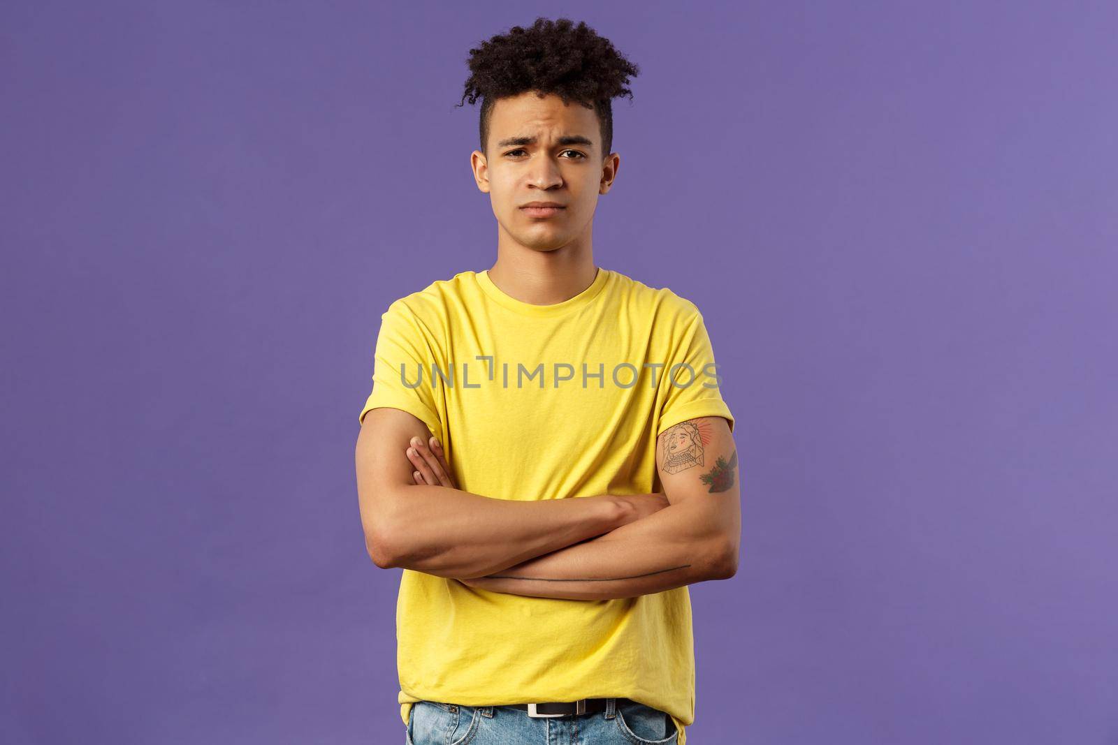 Close-up portrait of skeptical, unimpressed young man with dreads, look judgemental and uninterested, cross arms chest, go on impress me, smirk disappointed, purple background.