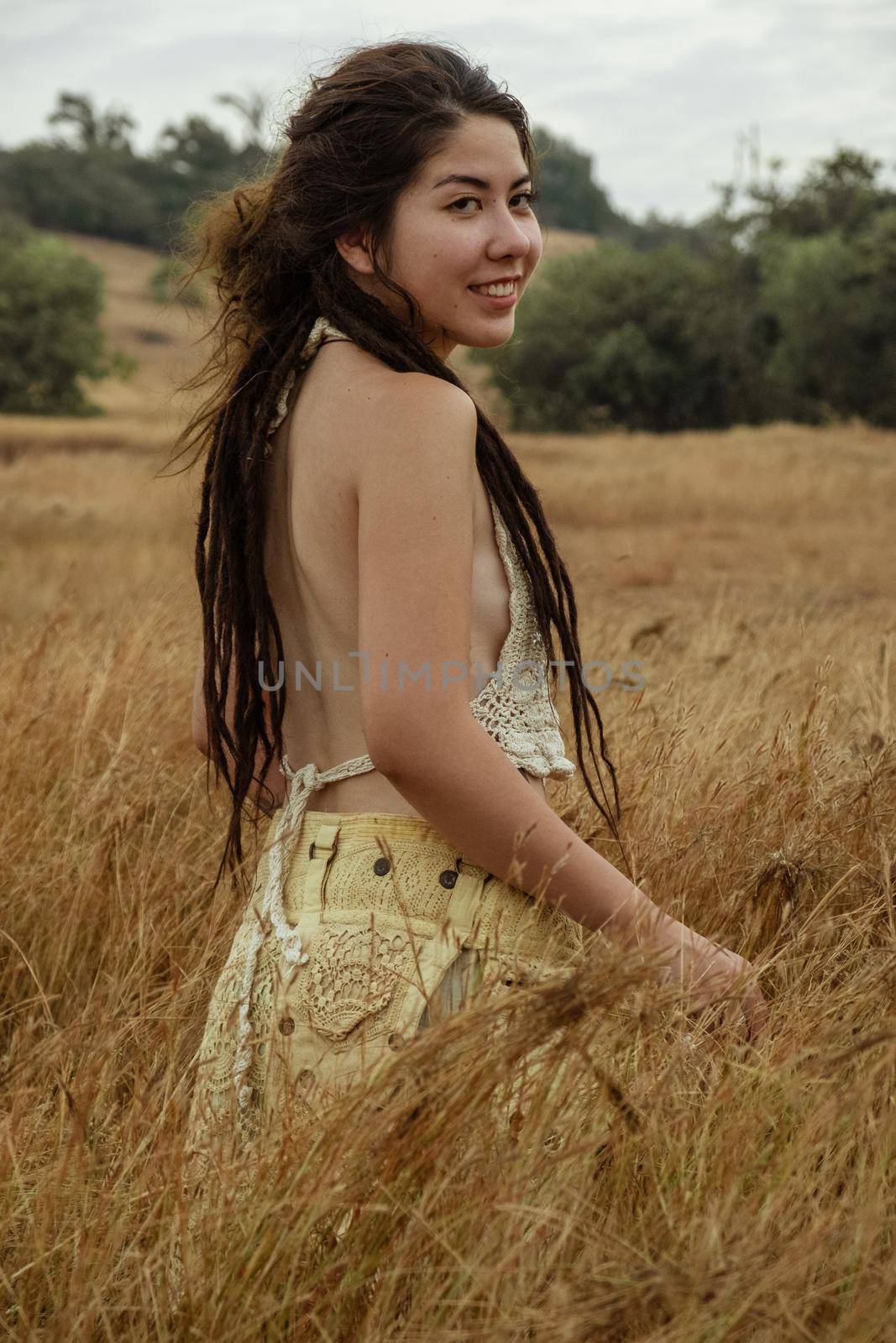 Portrait Of Smiling Young Woman Standing On Dry Grass