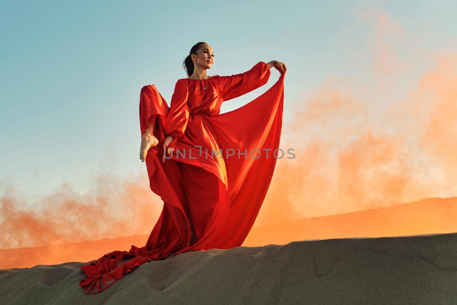 Woman in red dress dancing in the desert by snep_photo