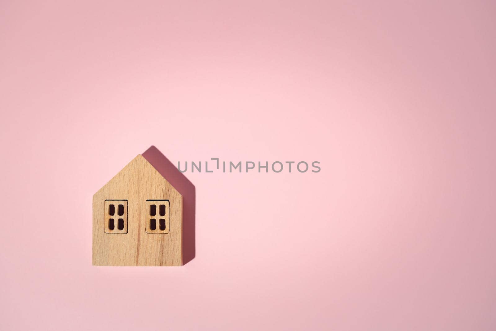 Wooden house model on pink background with copy space for housing concept