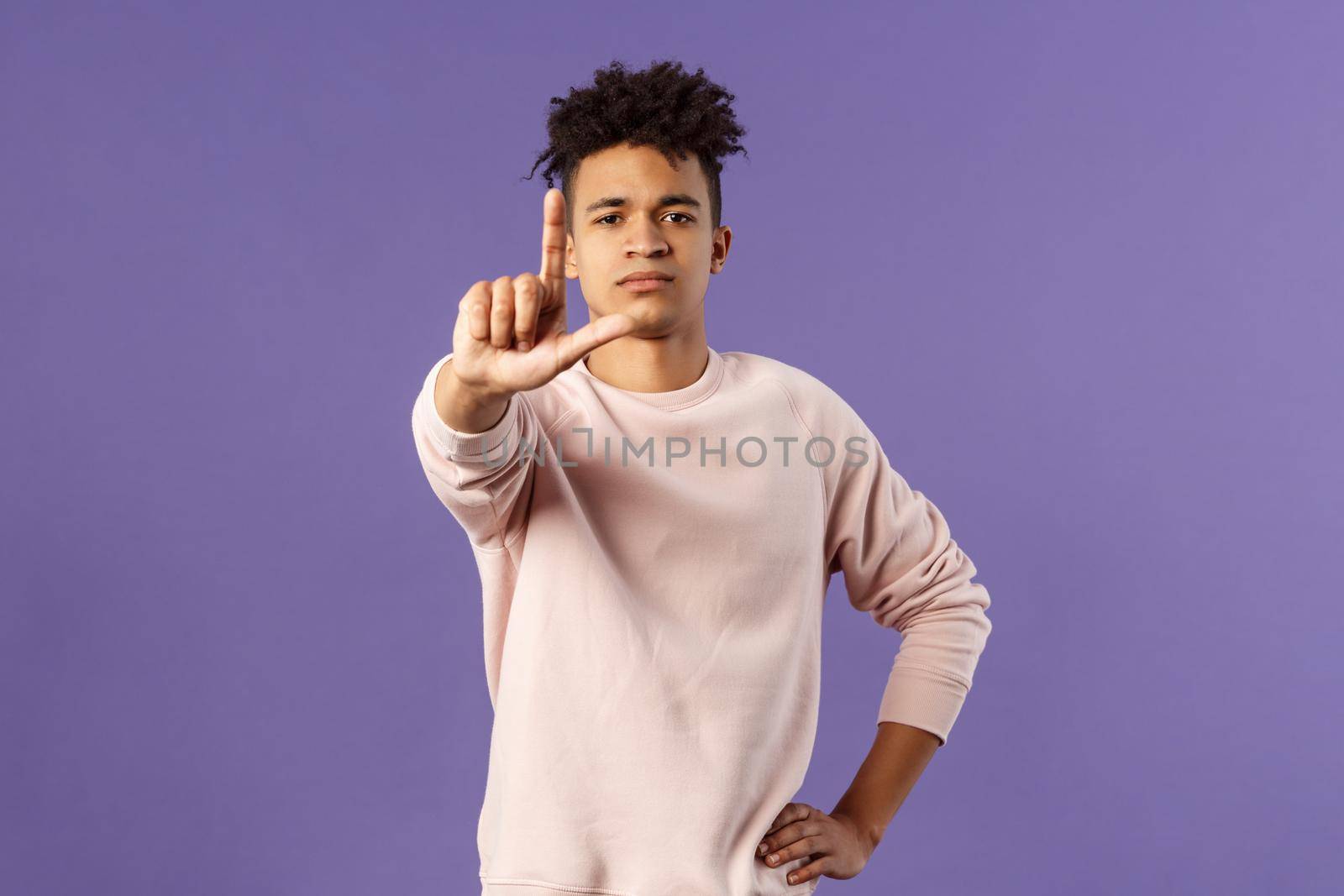Not so fast, stop. Portrait of young serious-looking hispanic elder brother scolding sibling, forbid coming outside, shaking finger with serious confident face, prohibit action, purple background by Benzoix