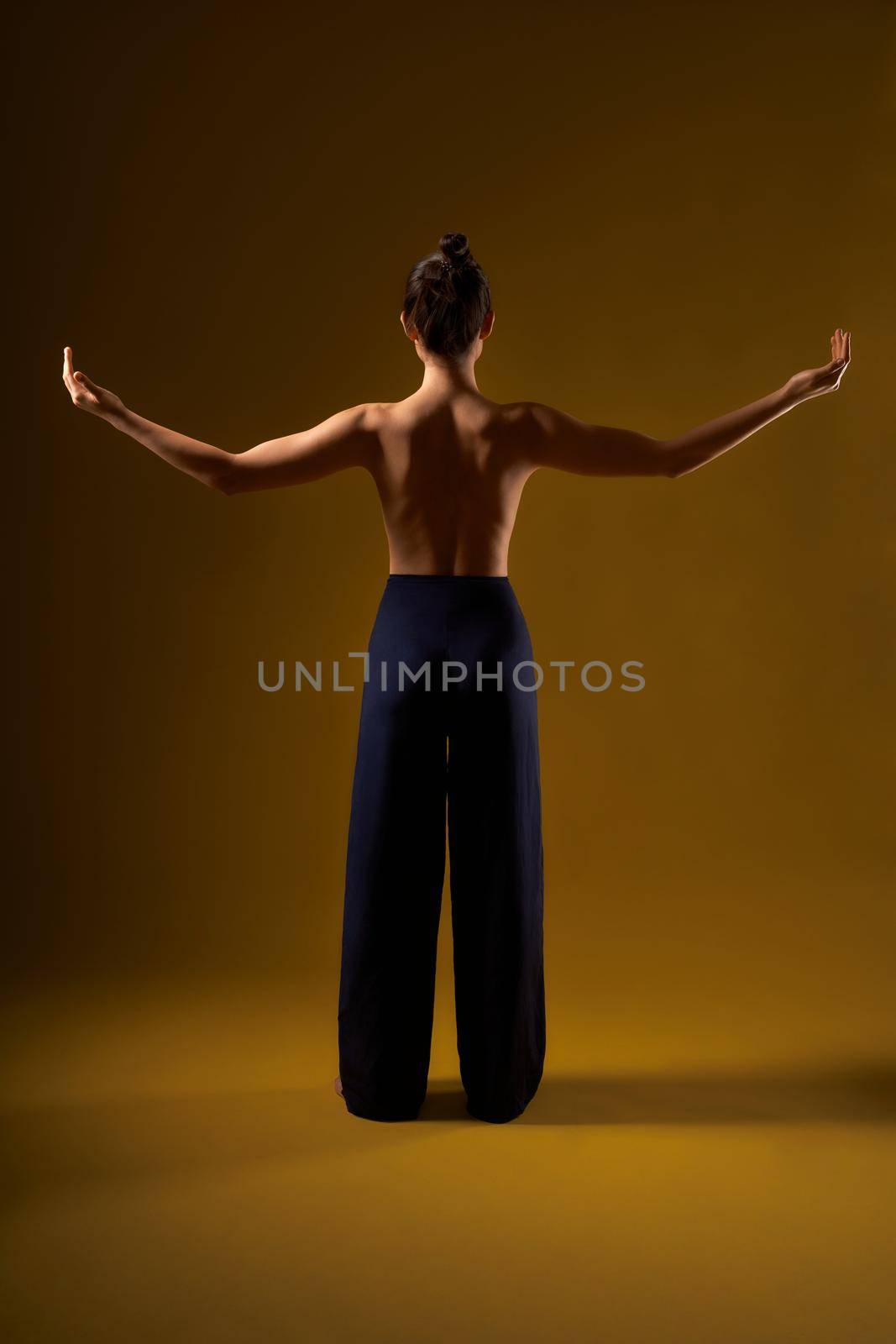 Brunette with hair bun doing yoga. by SerhiiBobyk