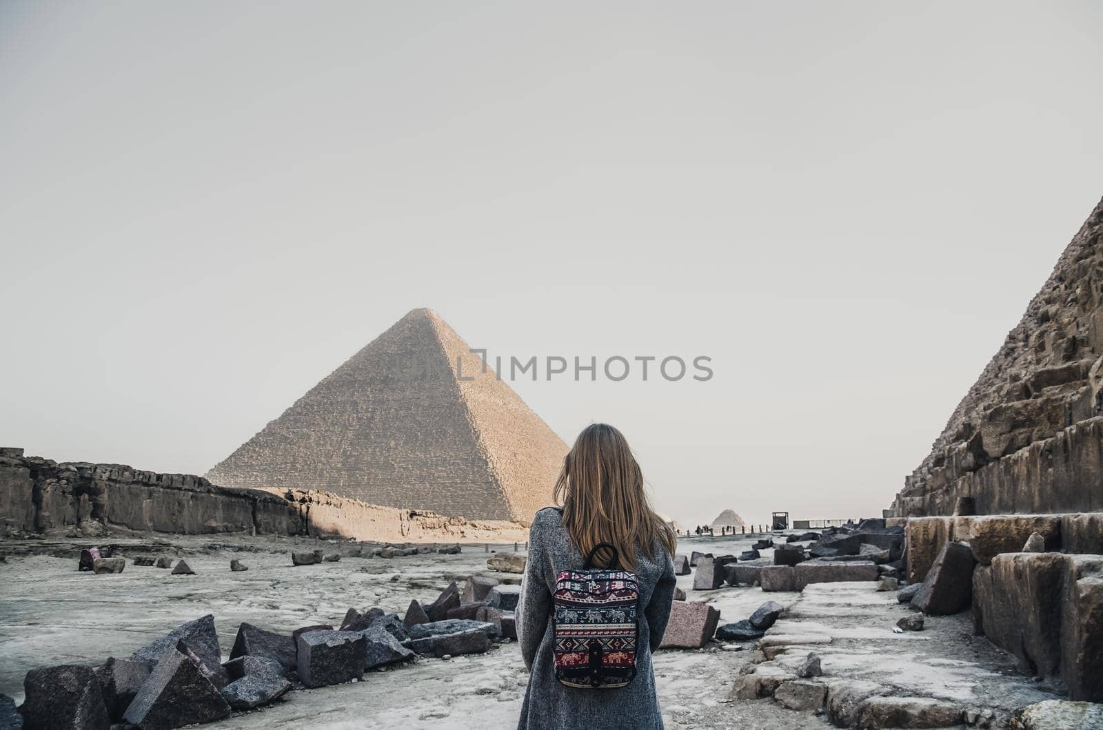 A European blonde walks near the pyramids in the desert in Cairo. The girl against the background of ancient buildings in Giza.