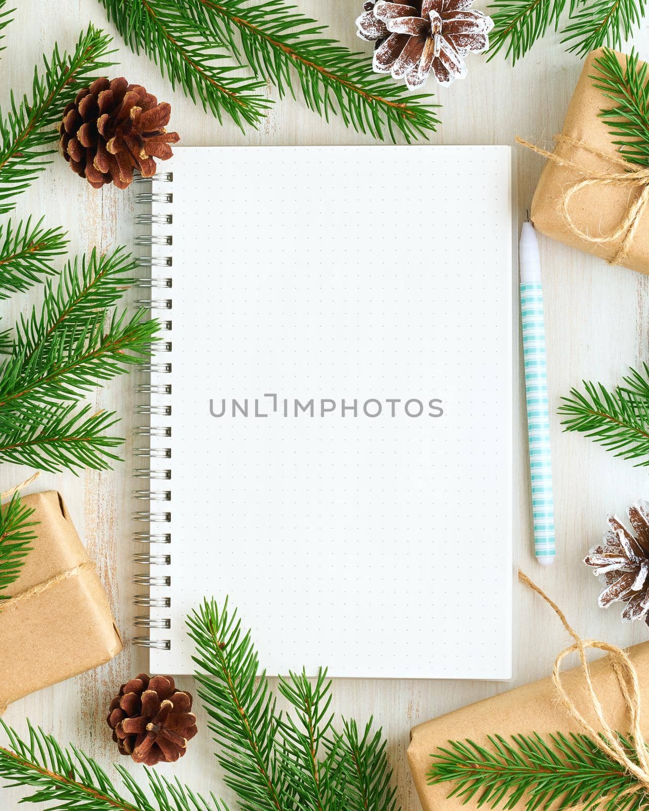 White open notepad, bullet journal for wish list and Christmas decoration on white wooden background, flat lay, copy space. Hand crafted, plastic free, zero waste concept. Mock up, vertical