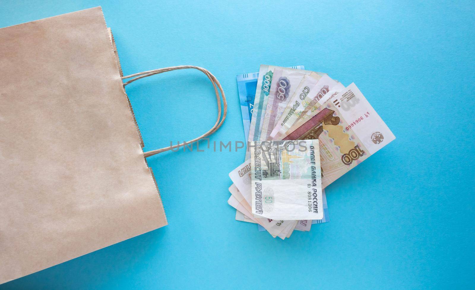 A bundle of Russian money and a paper bag on a blue background. Place for your text.