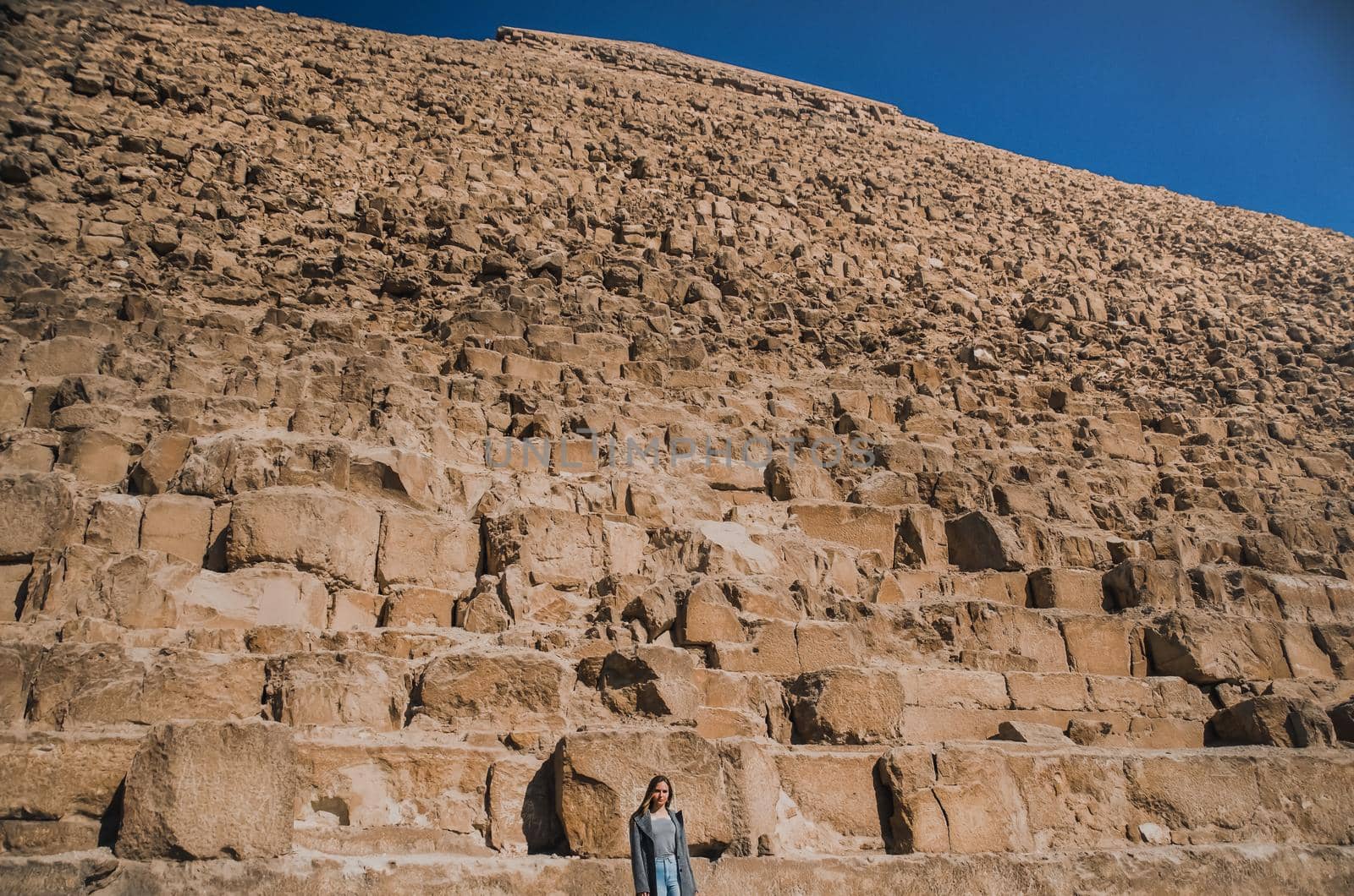 A European blonde walks near the pyramids in the desert in Cairo. The girl against the background of ancient buildings in Giza. Egyptian Sphinx