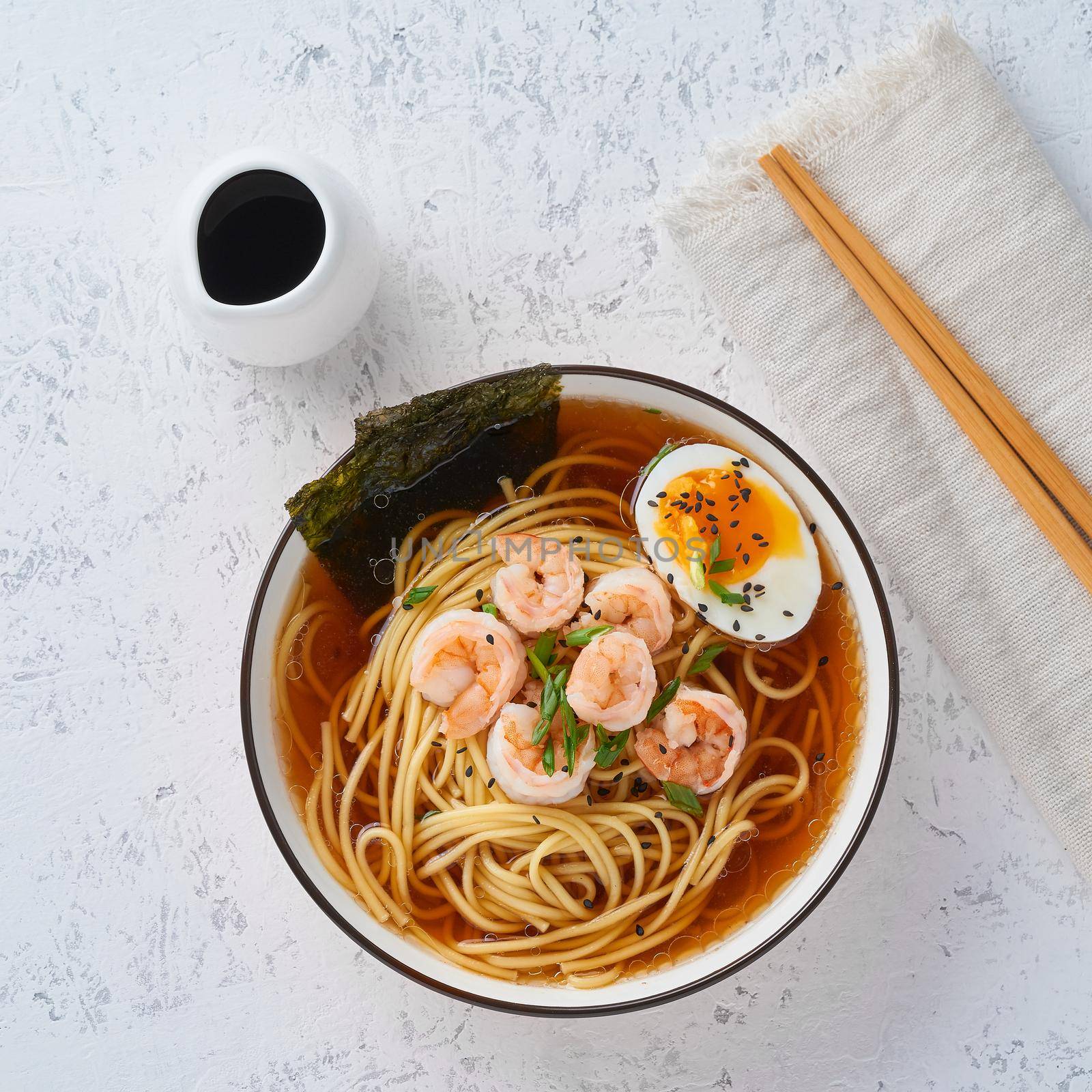 Asian soup with a noodles, ramen with shrimps. White stone table, top view