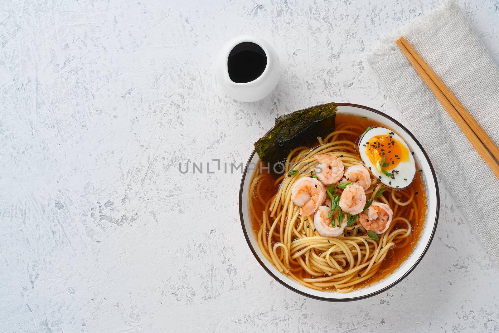 Asian soup with a noodles, ramen with shrimps, copy space. White stone table, top view