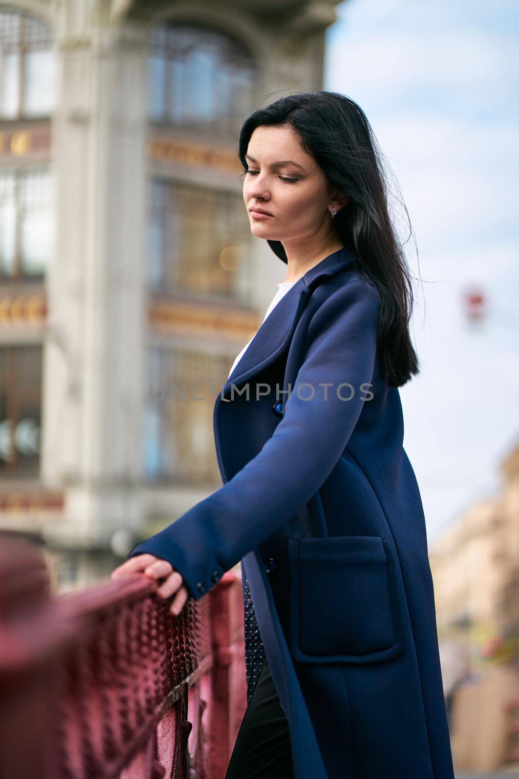 Portrait close-up of beautiful intelligent brunette who walks down street of St. Petersburg in city center. Charming thoughtful woman with long dark hair wanders alone, immersed in thoughts, vertical