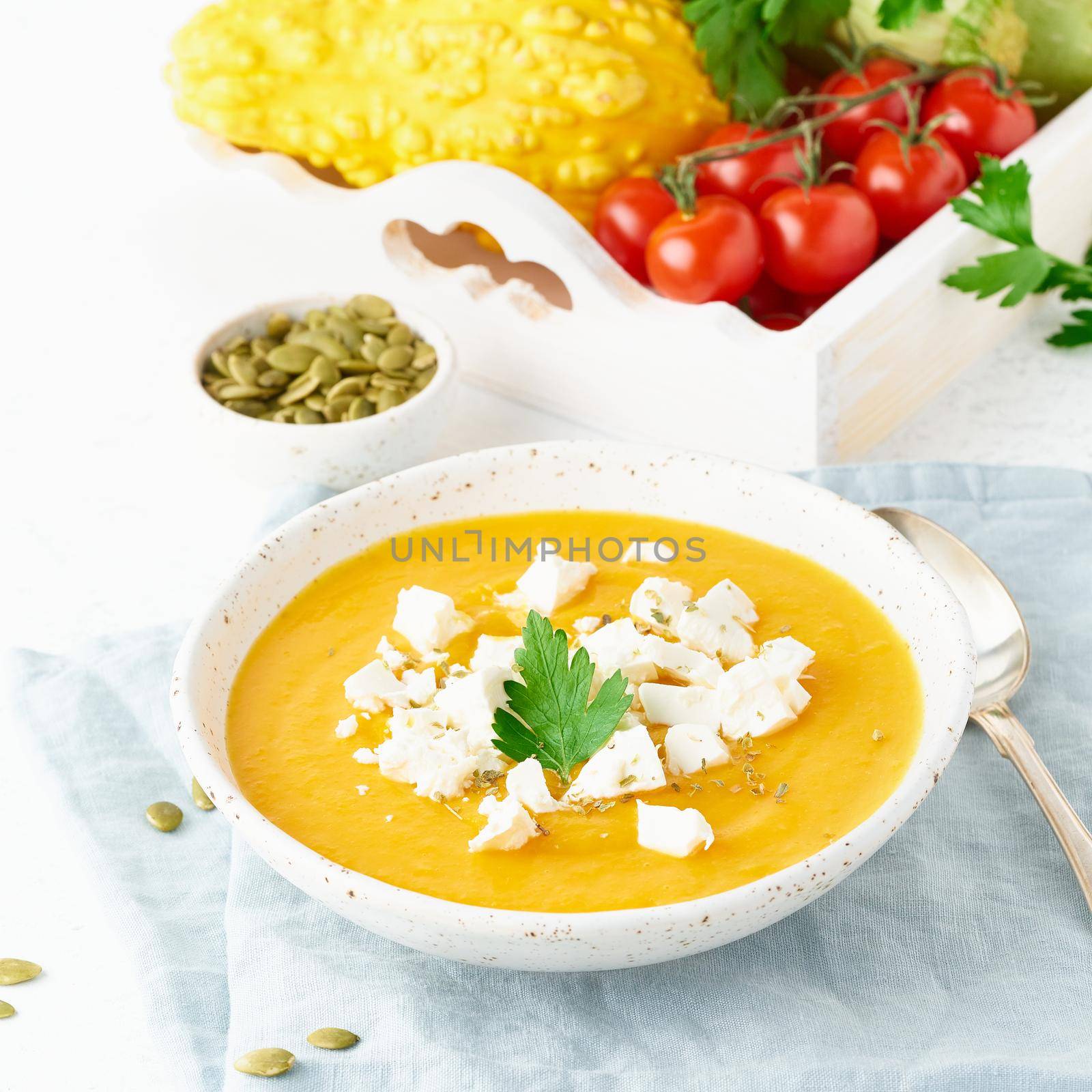 Pumpkin cream soup with feta cheese, autumn homemade food, white background, closeup by NataBene