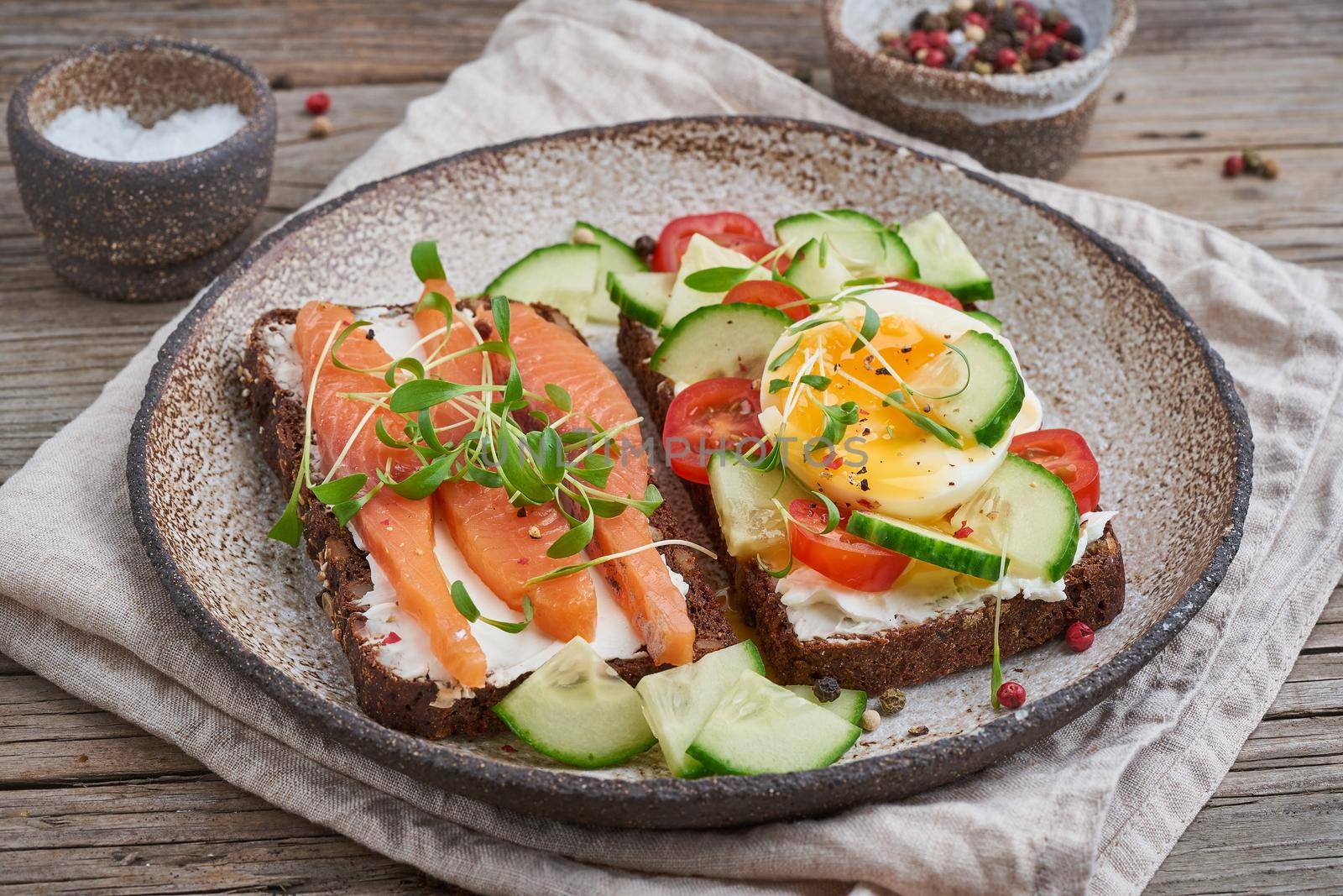 Smorrebrod - traditional Danish sandwiches. Black rye bread with salmon, cream cheese, cucumber, tomatoes on a wooden background