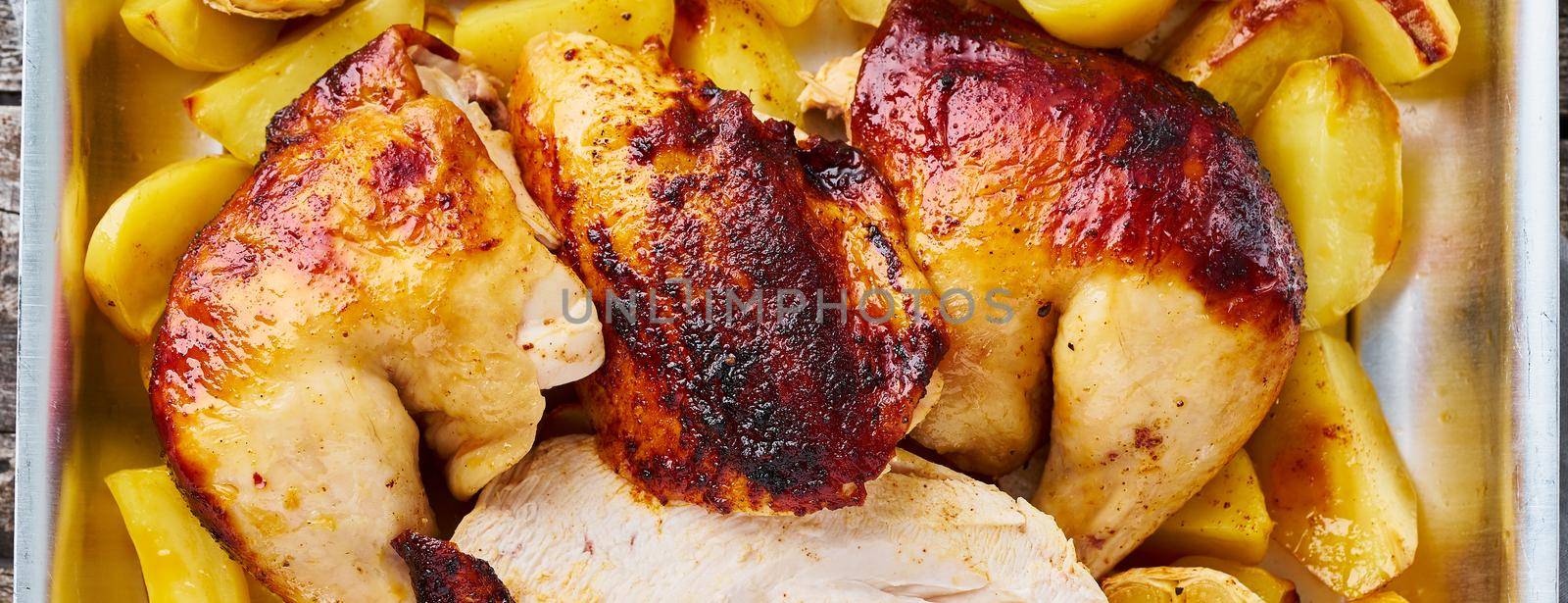 Long banner with Grilled chicken meat, leg, thigh with baked potatoes, garlic. Top view, close up. Gray old wooden table.