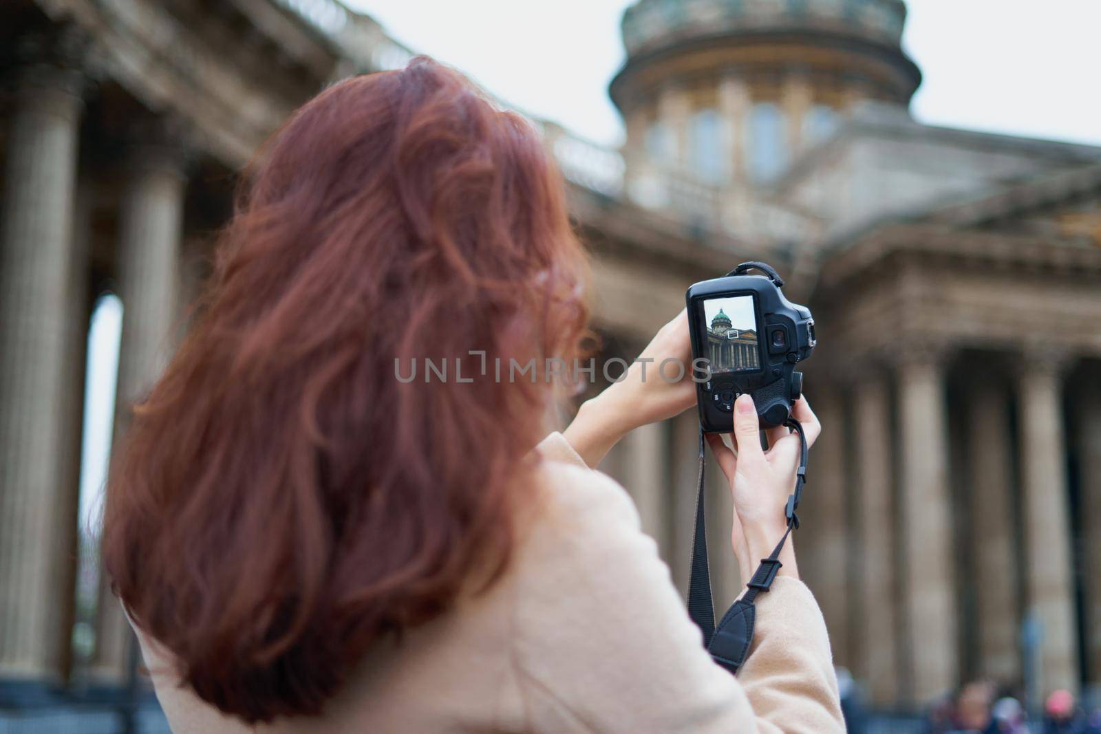 Unrecognizable person standing with his back turned and photographs sights, woman with long thick dark hair, tourist in center of St. Petersburg. Focus on the camera